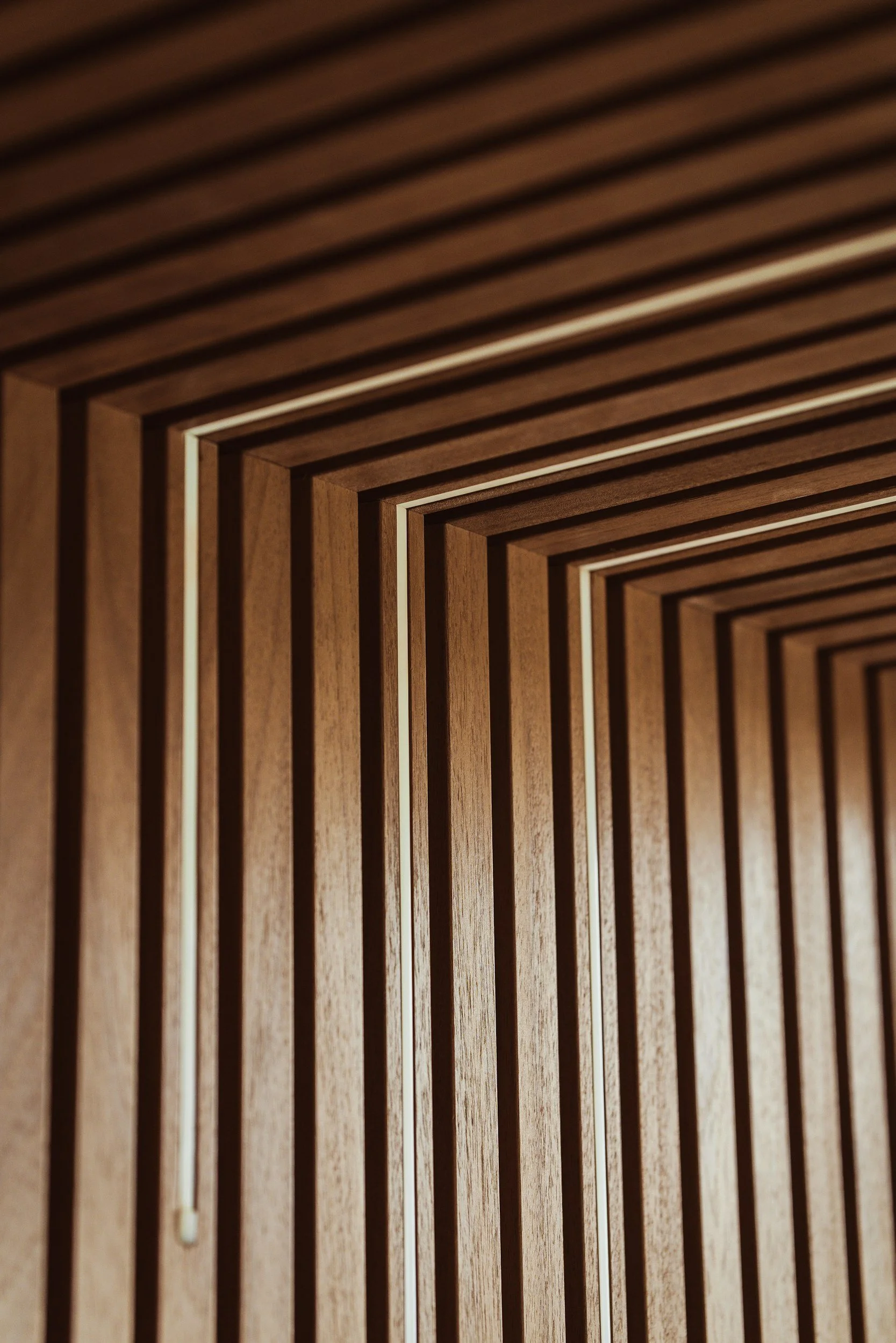 Close-up view of a wooden geometric pattern featuring rectangular slats arranged in a layered, repeating design.