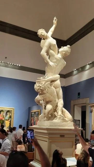 Michelangelo's David in Florence, a dramatic piece of art, displayed in an art gallery with visitors observing around it.