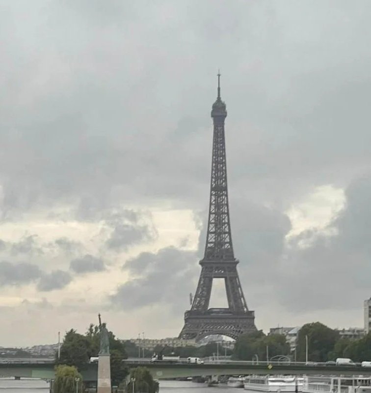 The Eiffel Tower in Paris under a cloudy sky.
