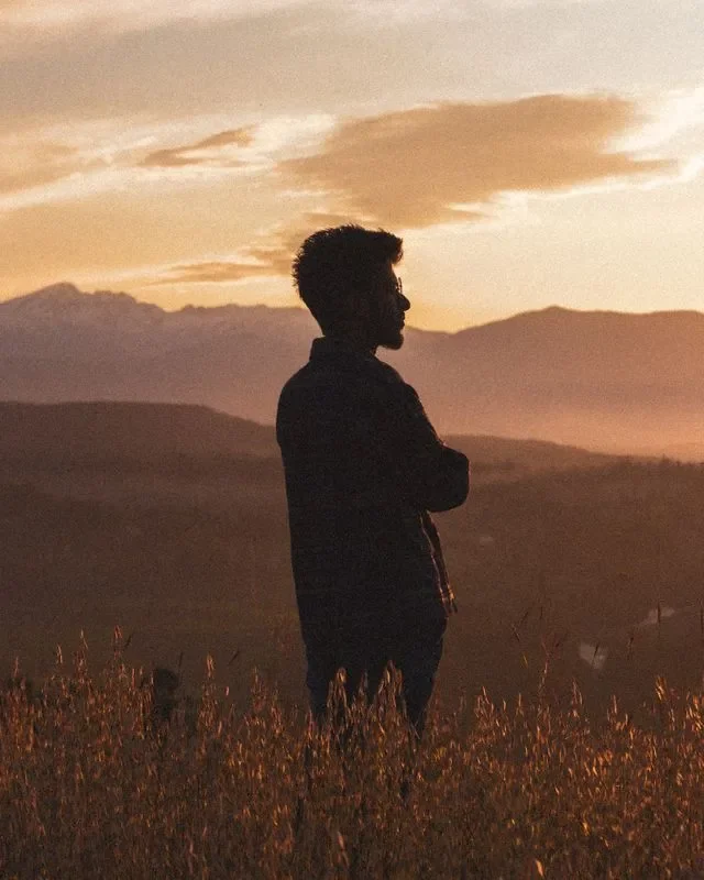 A man at sunset with mountains behind him