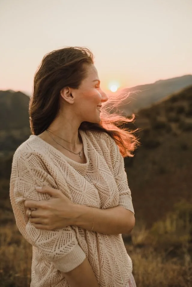 A woman smiling outside at sunset