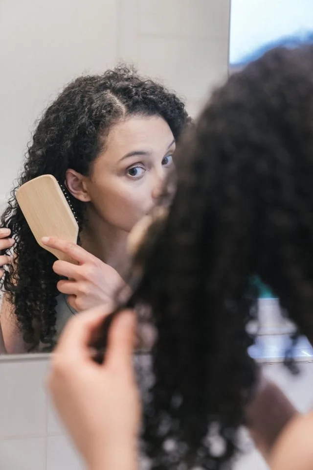 A person combing their hair in a mirror