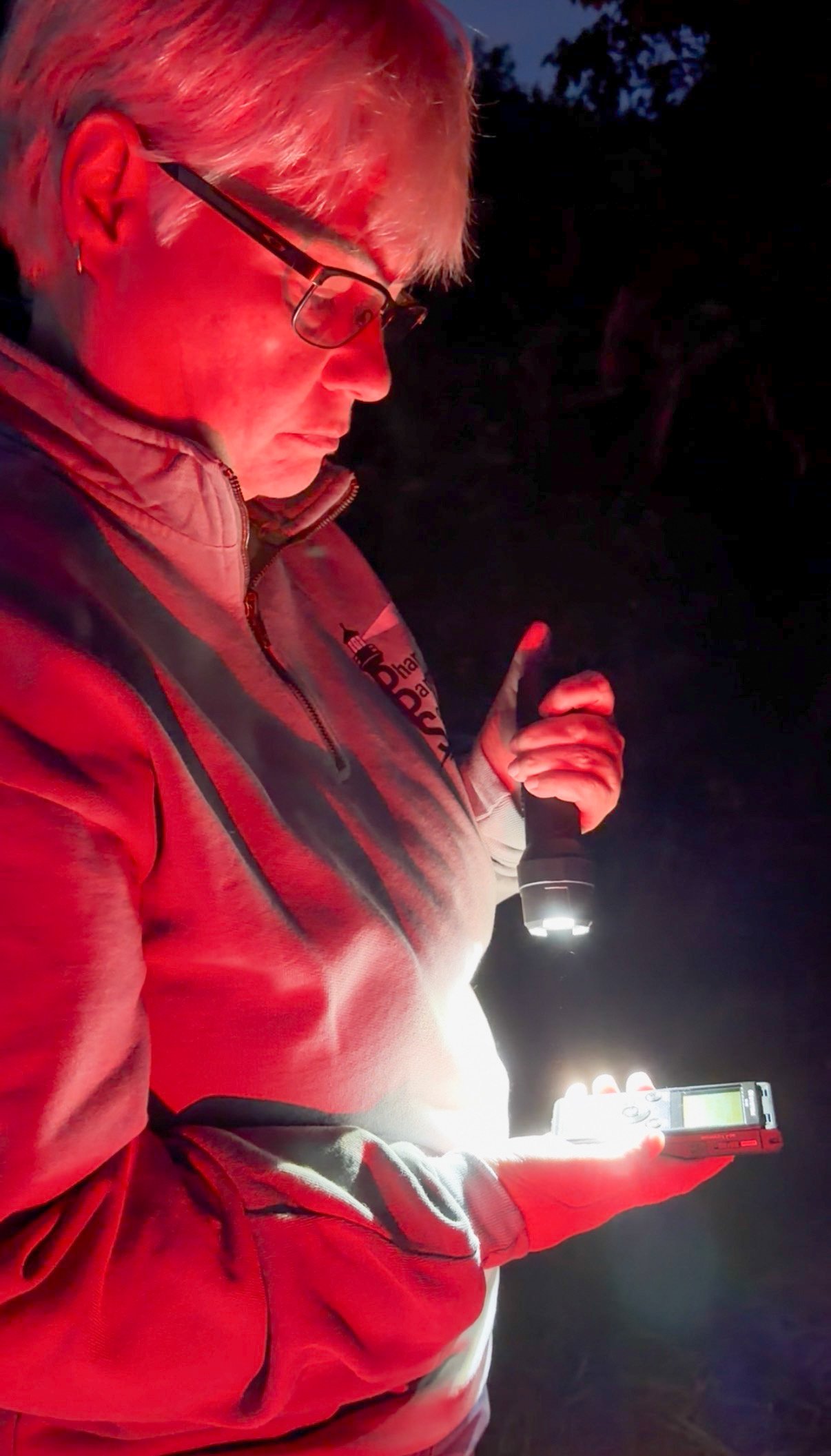 Nicole Smith-Merry using paranormal investigation equipment during a nighttime investigation.