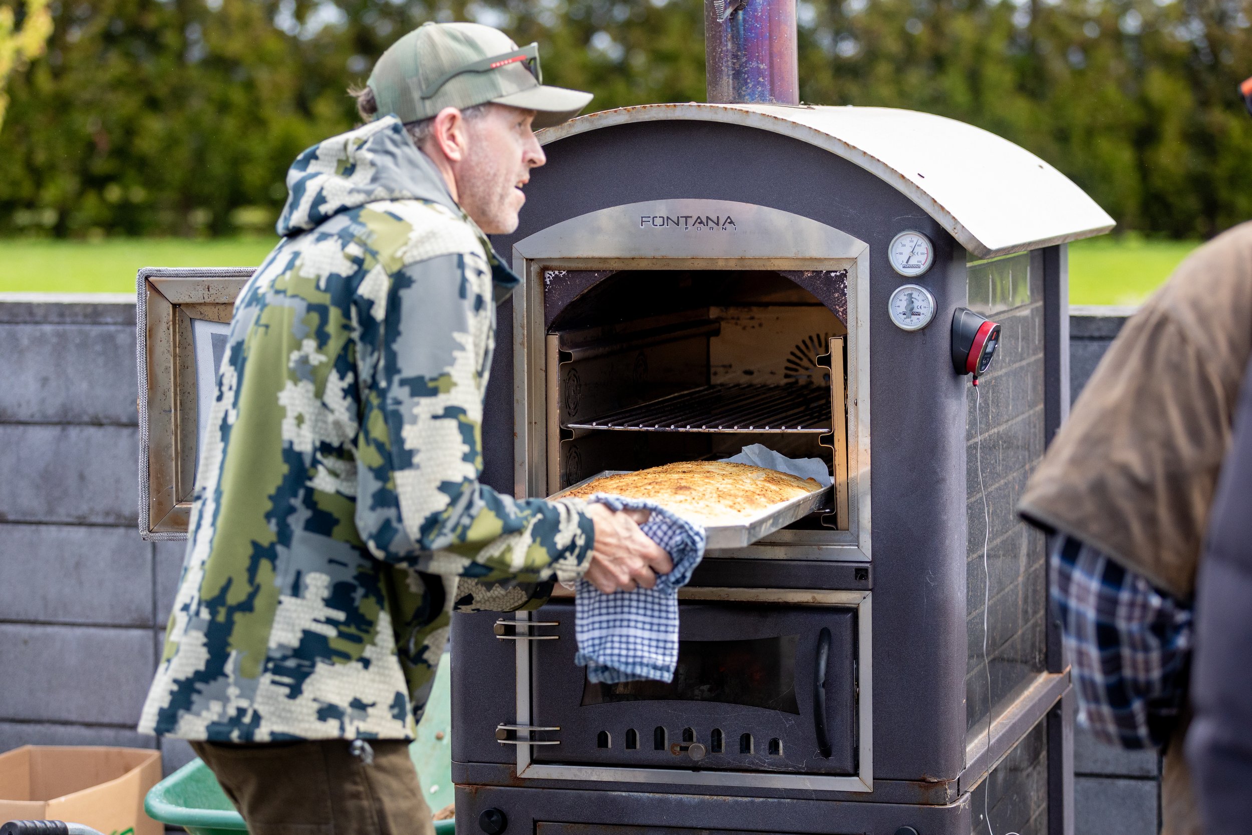 Your host Damian Murphy, baking bread in a large outdoor wood-fired oven.