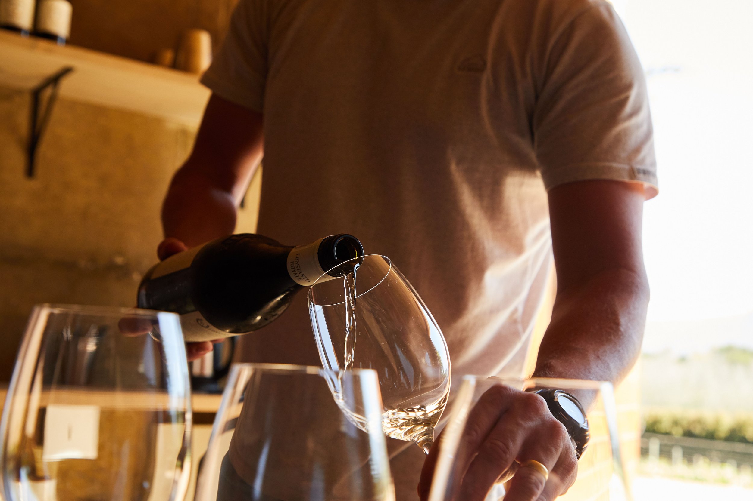 Person pouring red wine from a bottle into a tilted wine glass