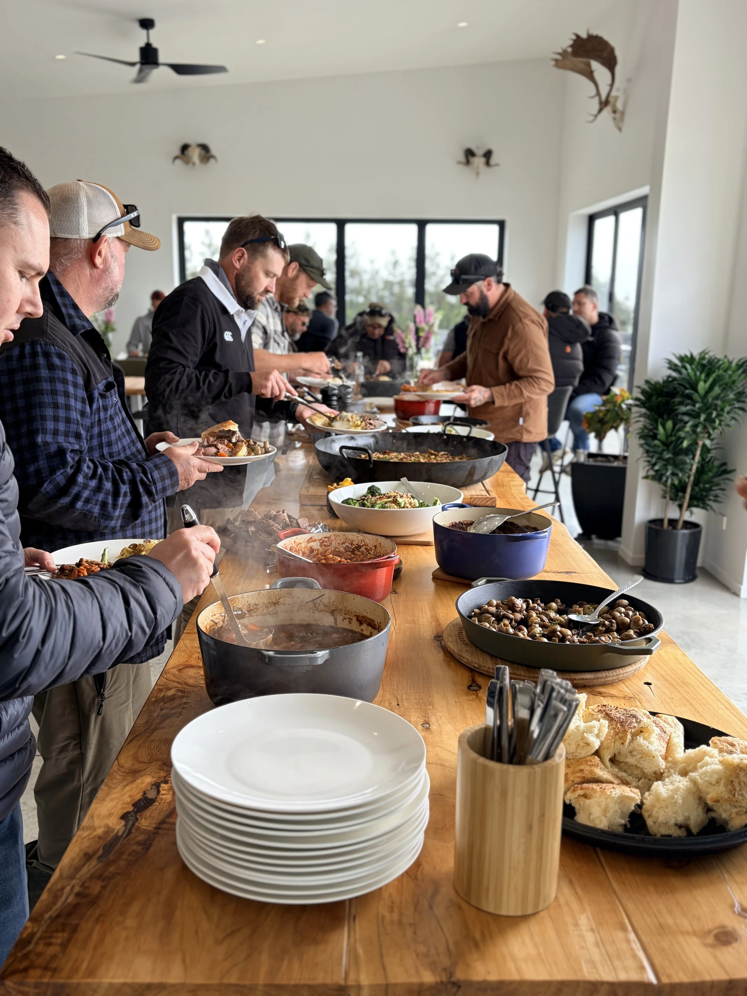 People serving themselves a buffet of homemade food at a communal dining table.