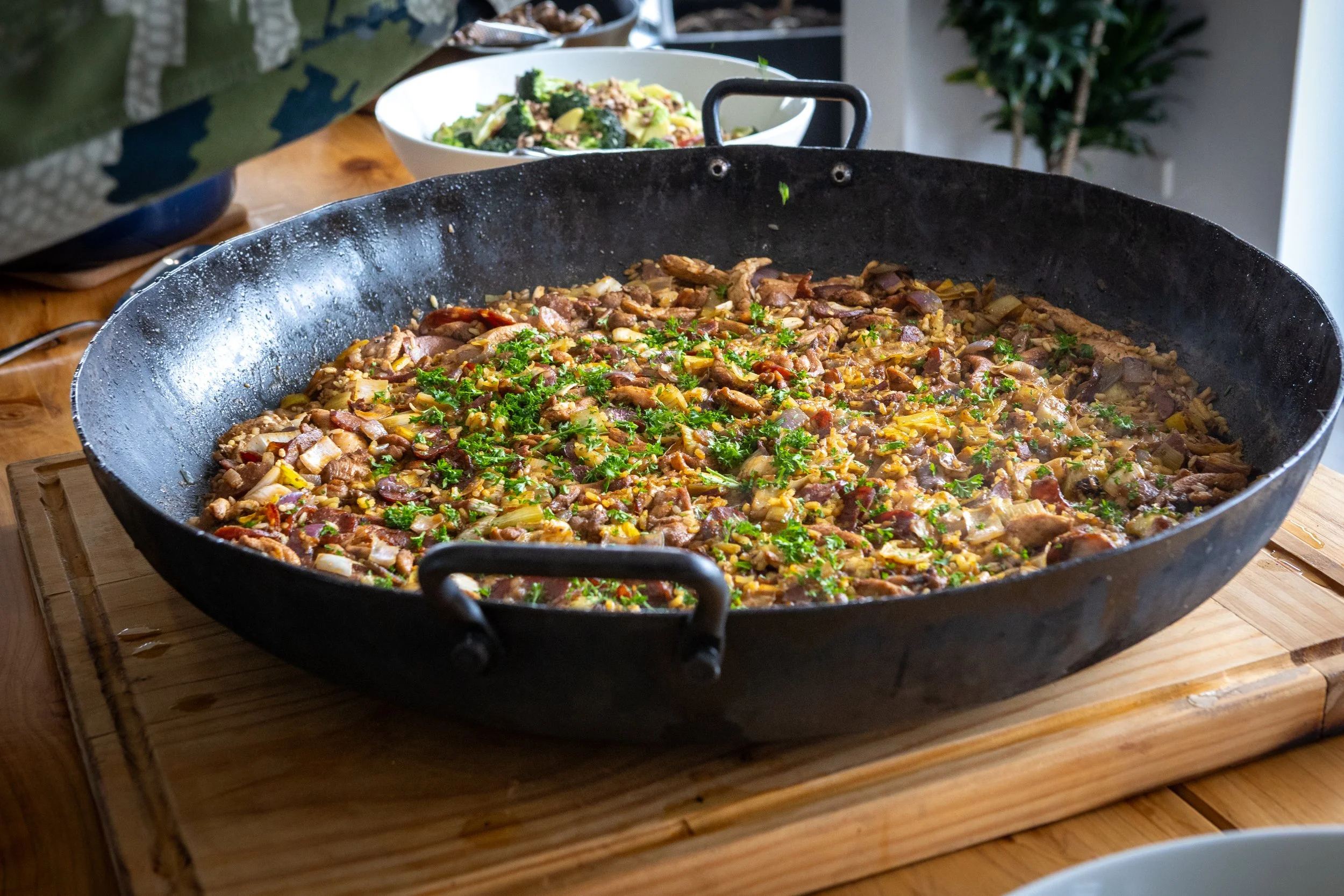 Large paella pan filled with rice, meat, vegetables, and fresh parsley