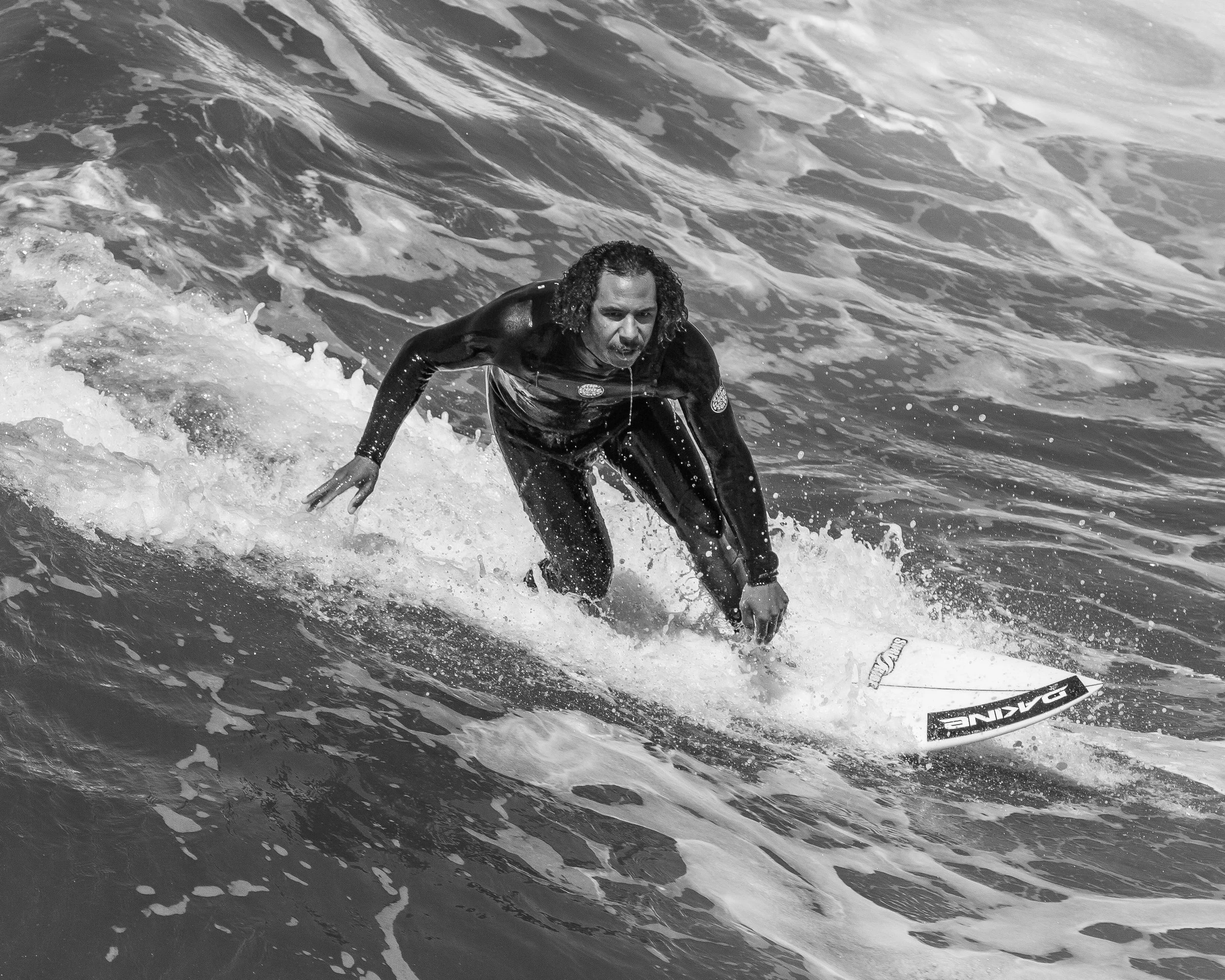 A person surfing on a wave in the ocean, wearing a wetsuit and holding a surfboard.