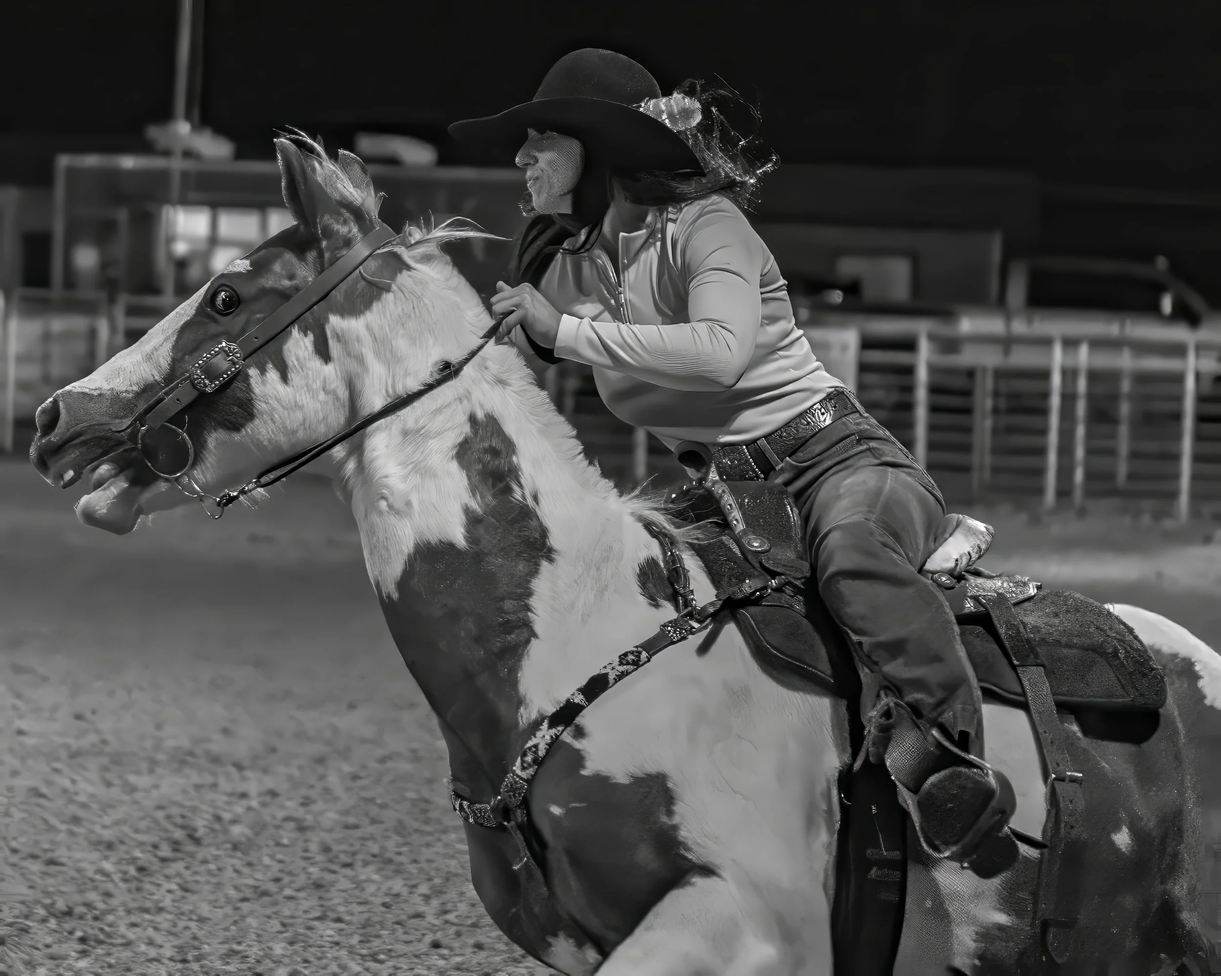 A person wearing a cowboy hat and western attire riding a horse at night, likely at a rodeo or horse riding event.