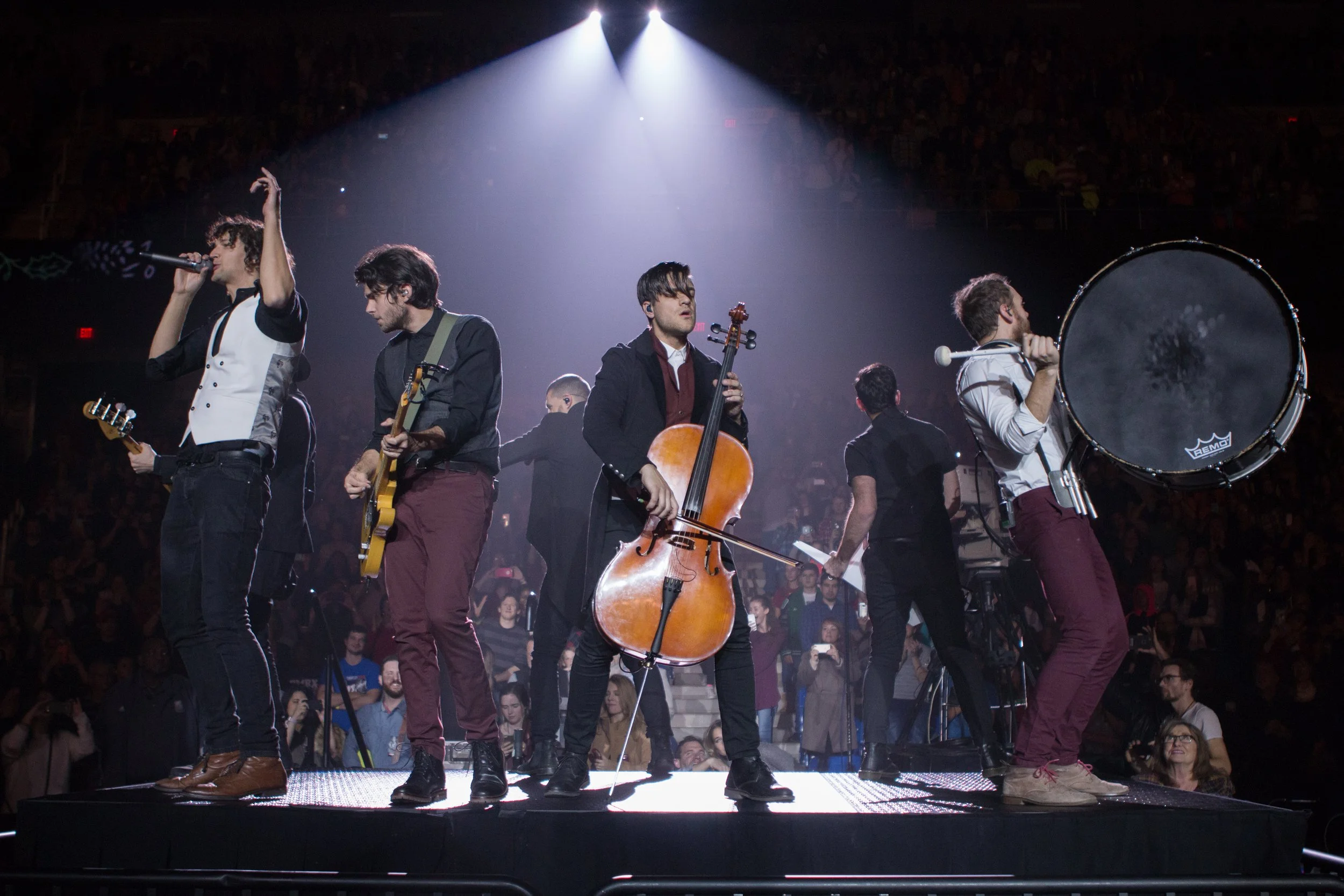 Musicians performing on stage in front of an audience with bright spotlights above them