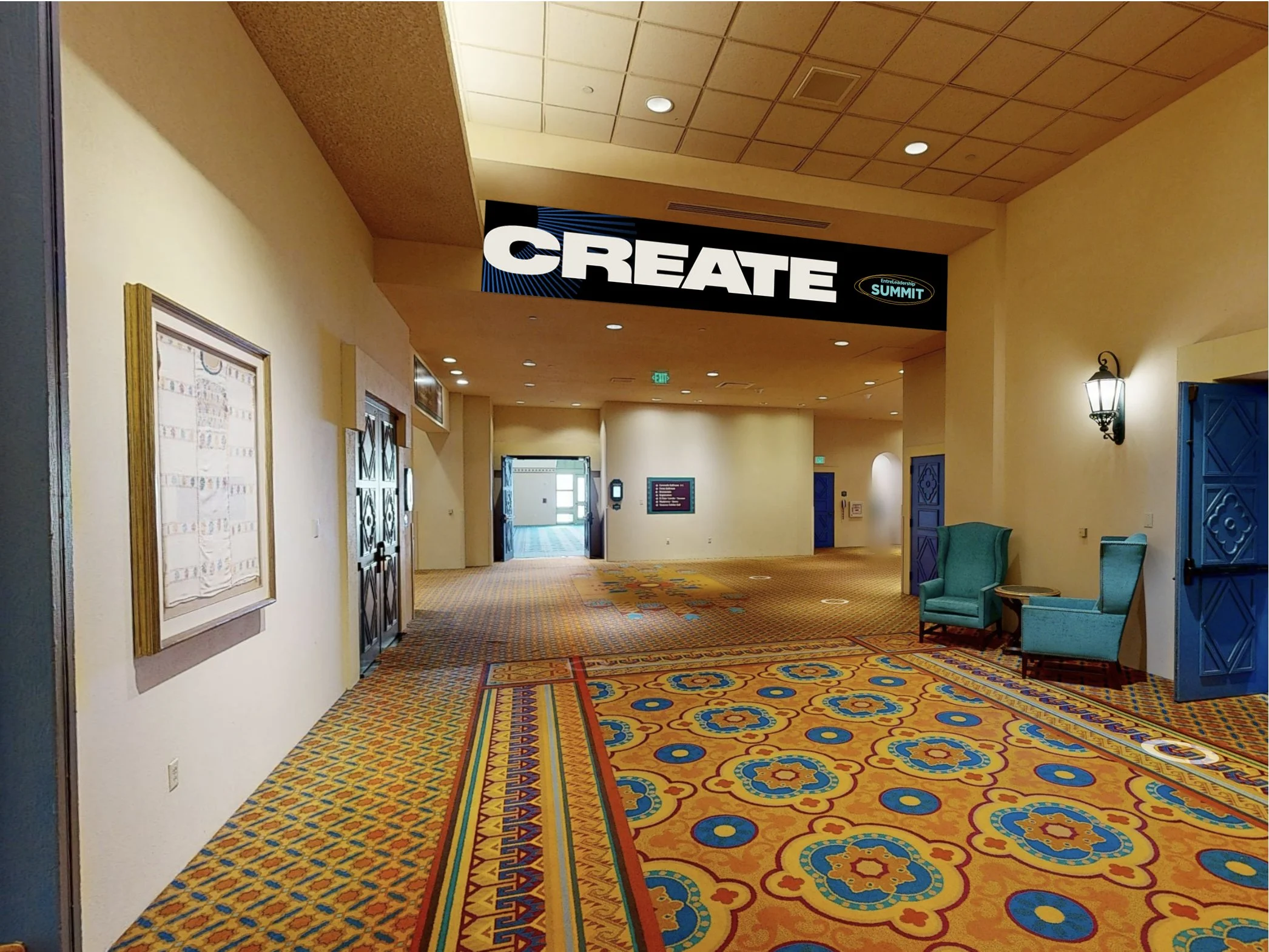 A hallway in a conference center with a colorful patterned carpet, blue chairs, and a large digital sign overhead that reads 'CREATE' with smaller text 'EntreLeadership Summit.'