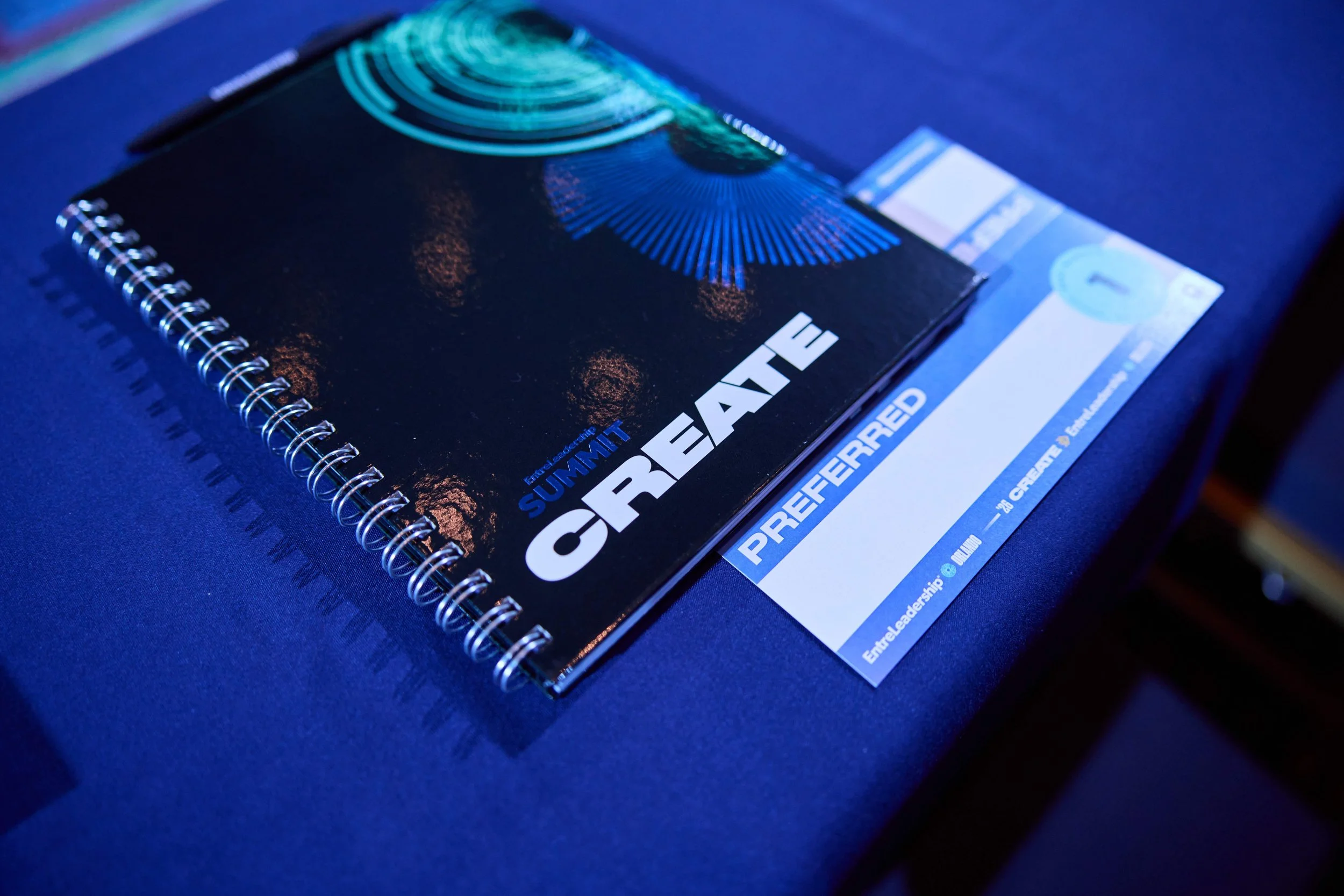 A spiral-bound workbook titled 'Summit Create' with a preferred nametent, lying on a blue surface.