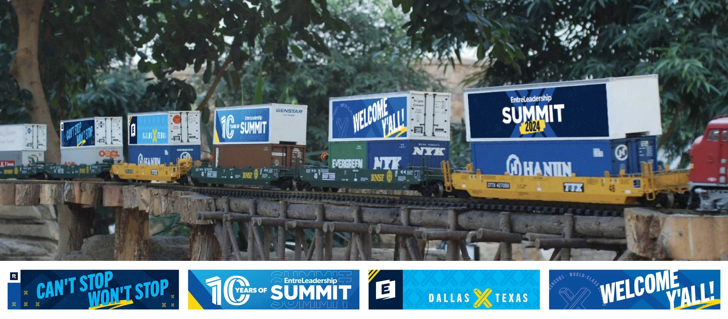 Model train with containers and banners for the EntreLeadership Summit 2024, displayed outdoors on a wooden platform.