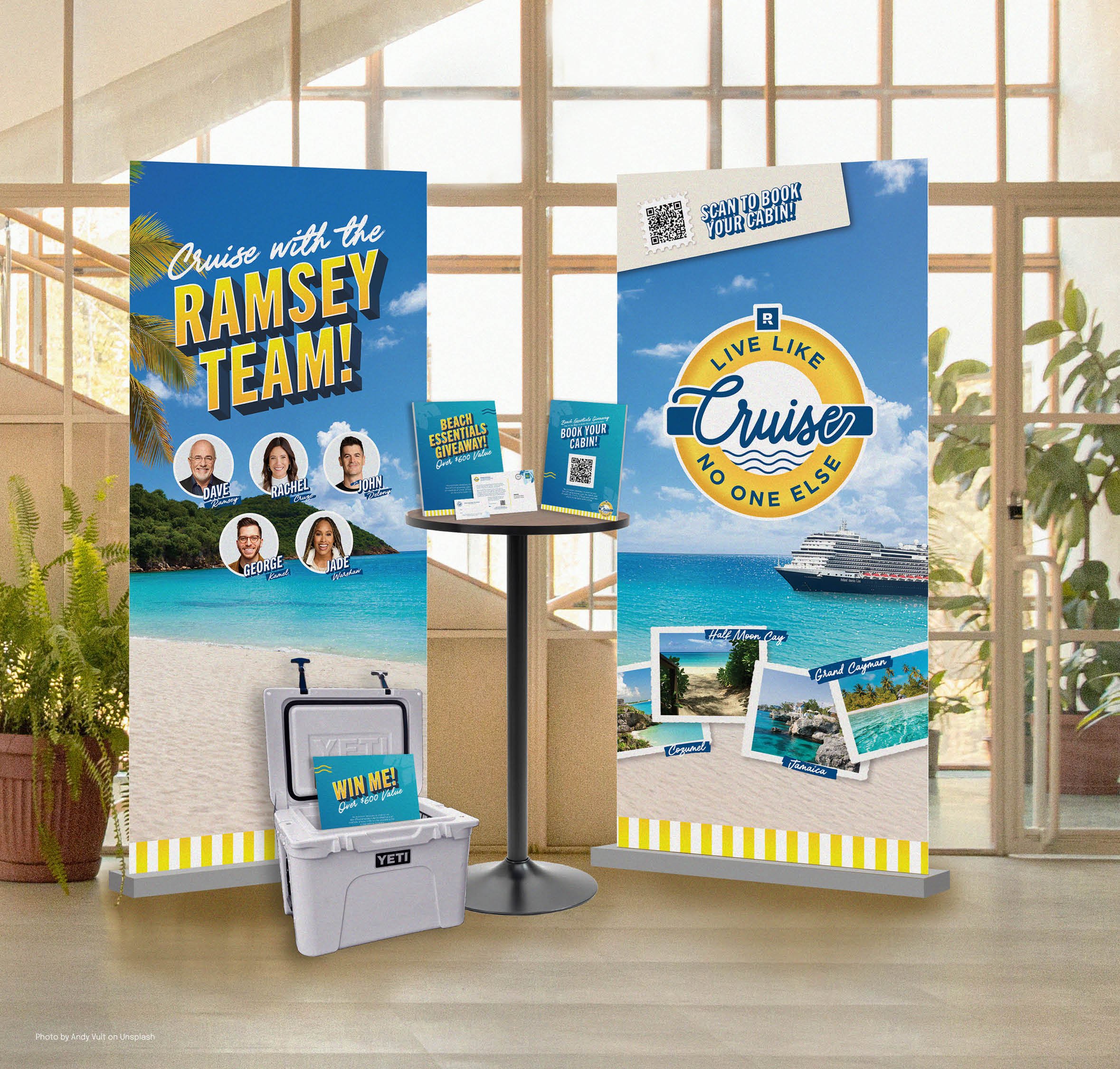 Signage and promotional materials for a cruise vacation, including a poster that says 'Cruise with the RAMSEY TEAM!' with photos of team members, a QR code to book a cabin, and a circular logo that says 'Live Like Cruise No One Else', along with trop