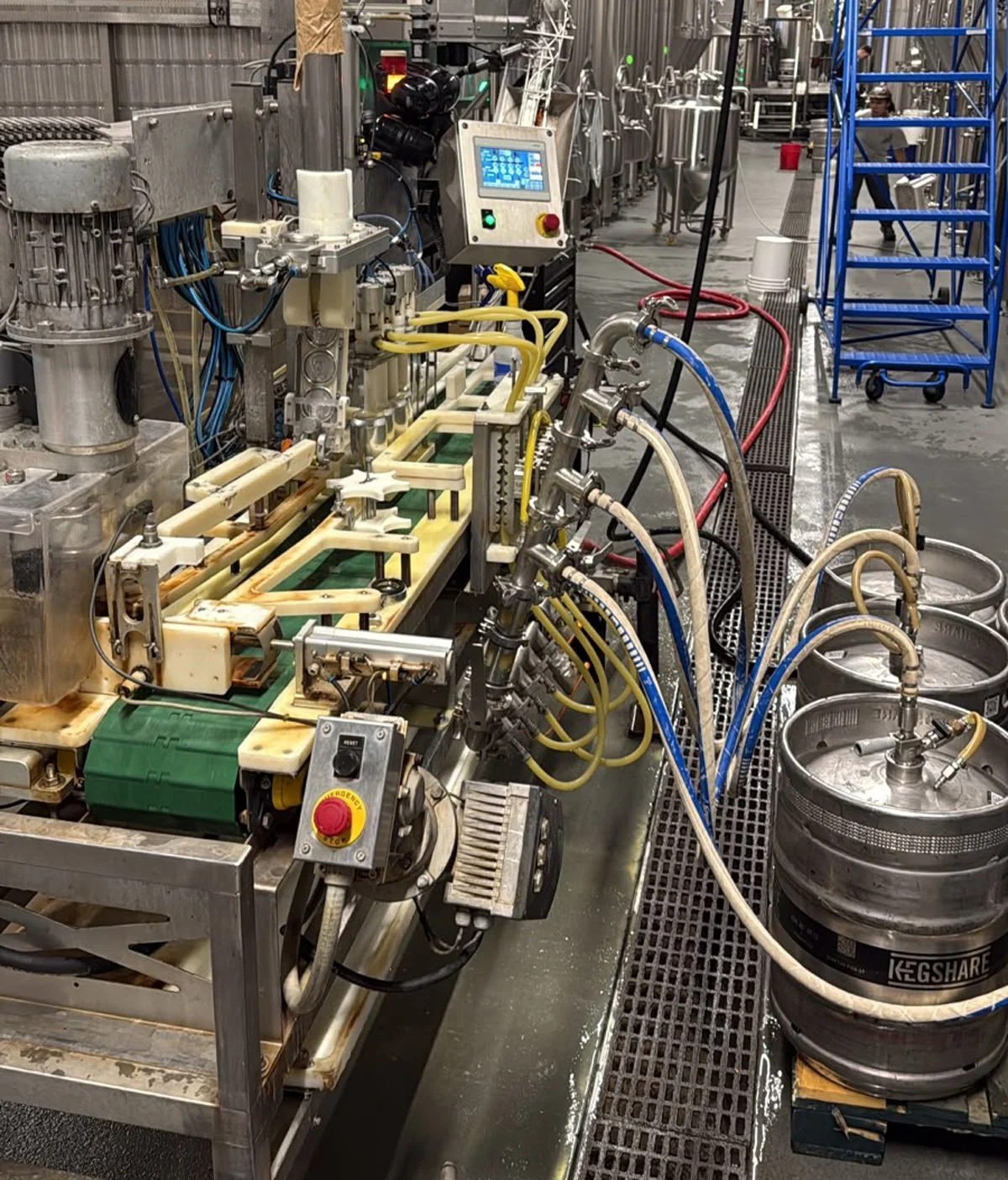 Industrial equipment with pipes, tubes, and tanks in a manufacturing or processing plant, including stainless steel components and a control panel.