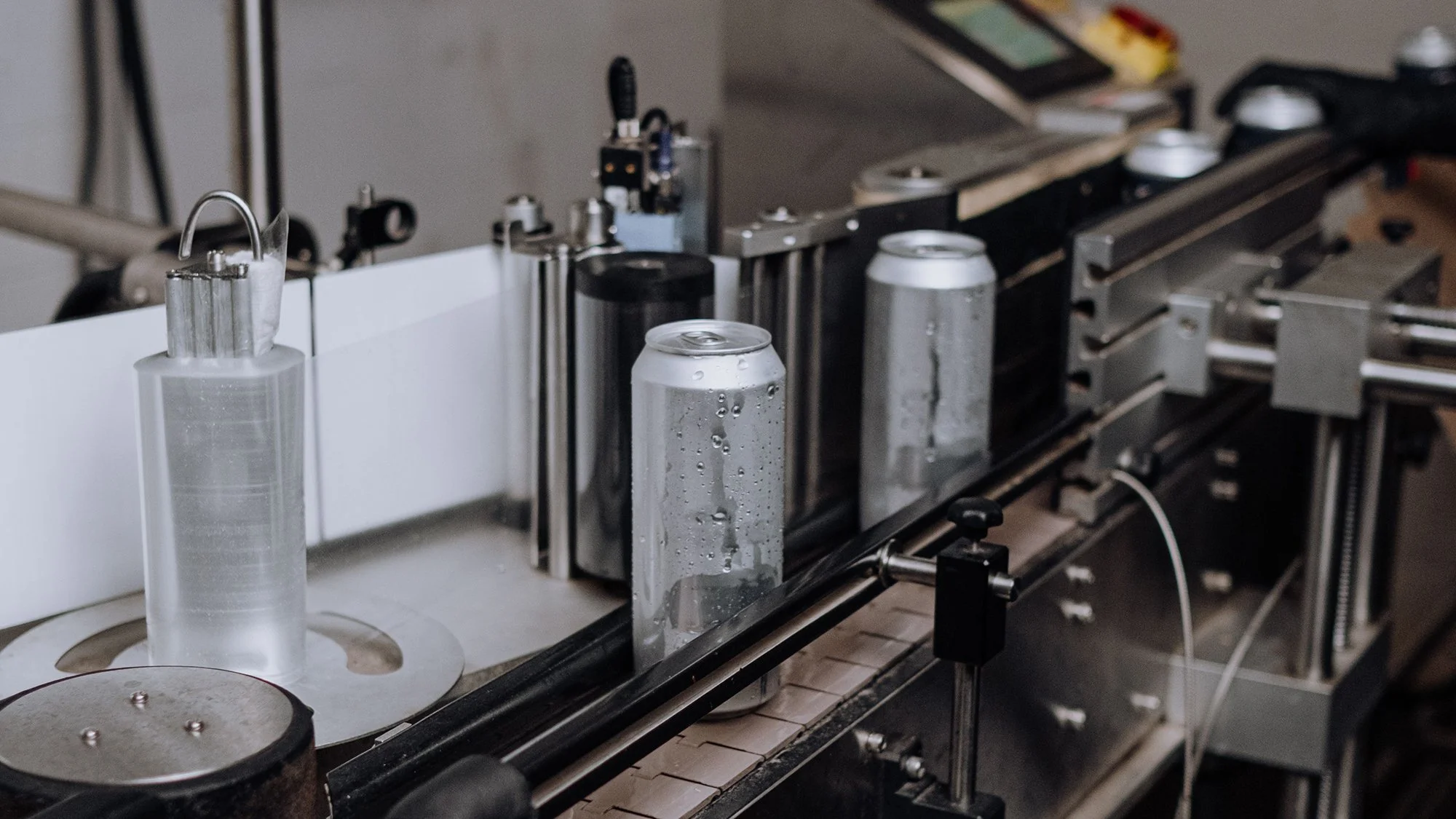 Automated production line filling cans with water, with water droplets on the cans.