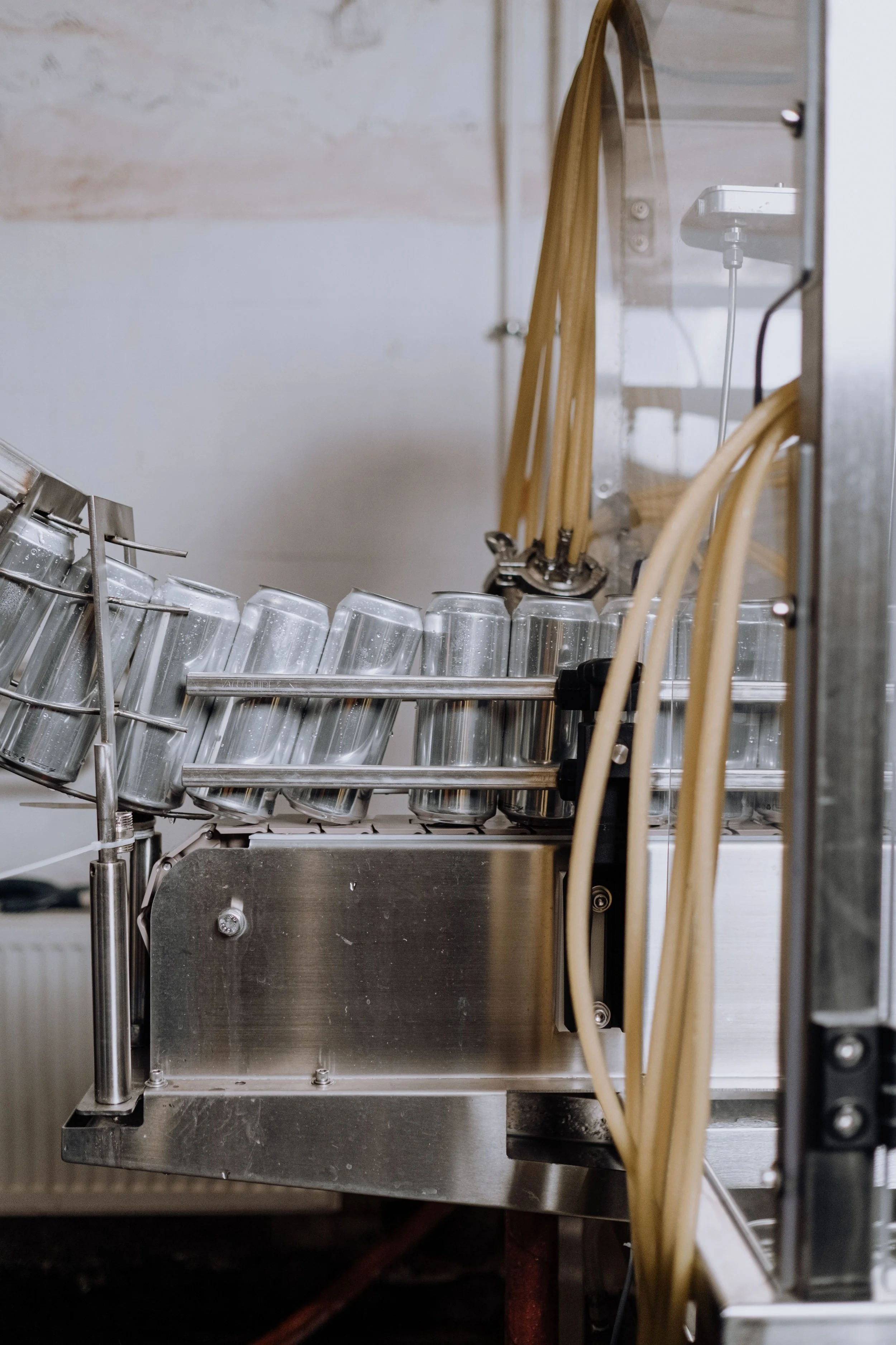 Close-up view of a metal beverage dispensing machine with multiple glass bottles and tubes connected to it.