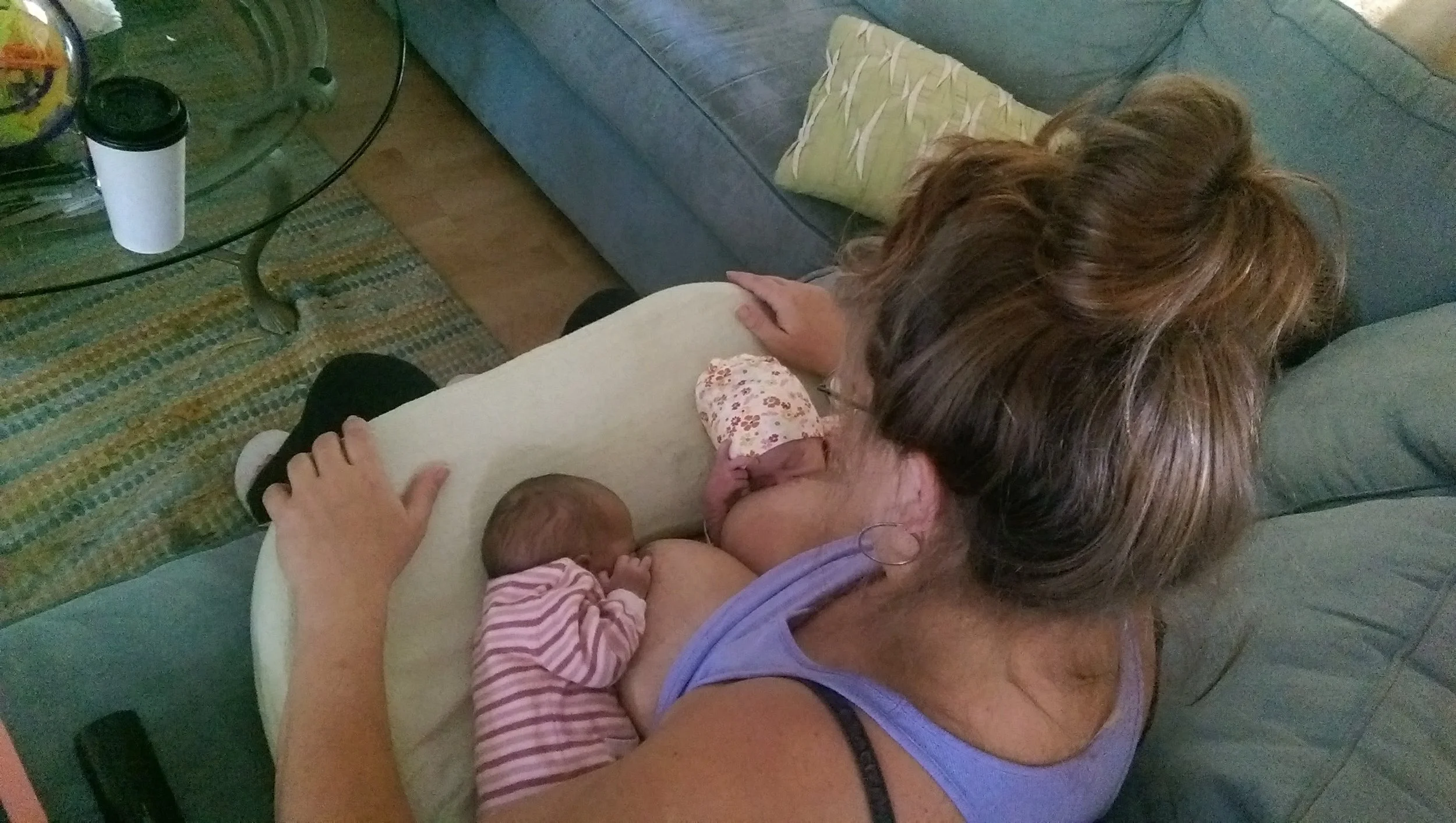 Woman sitting on couch feeding twins at her chest