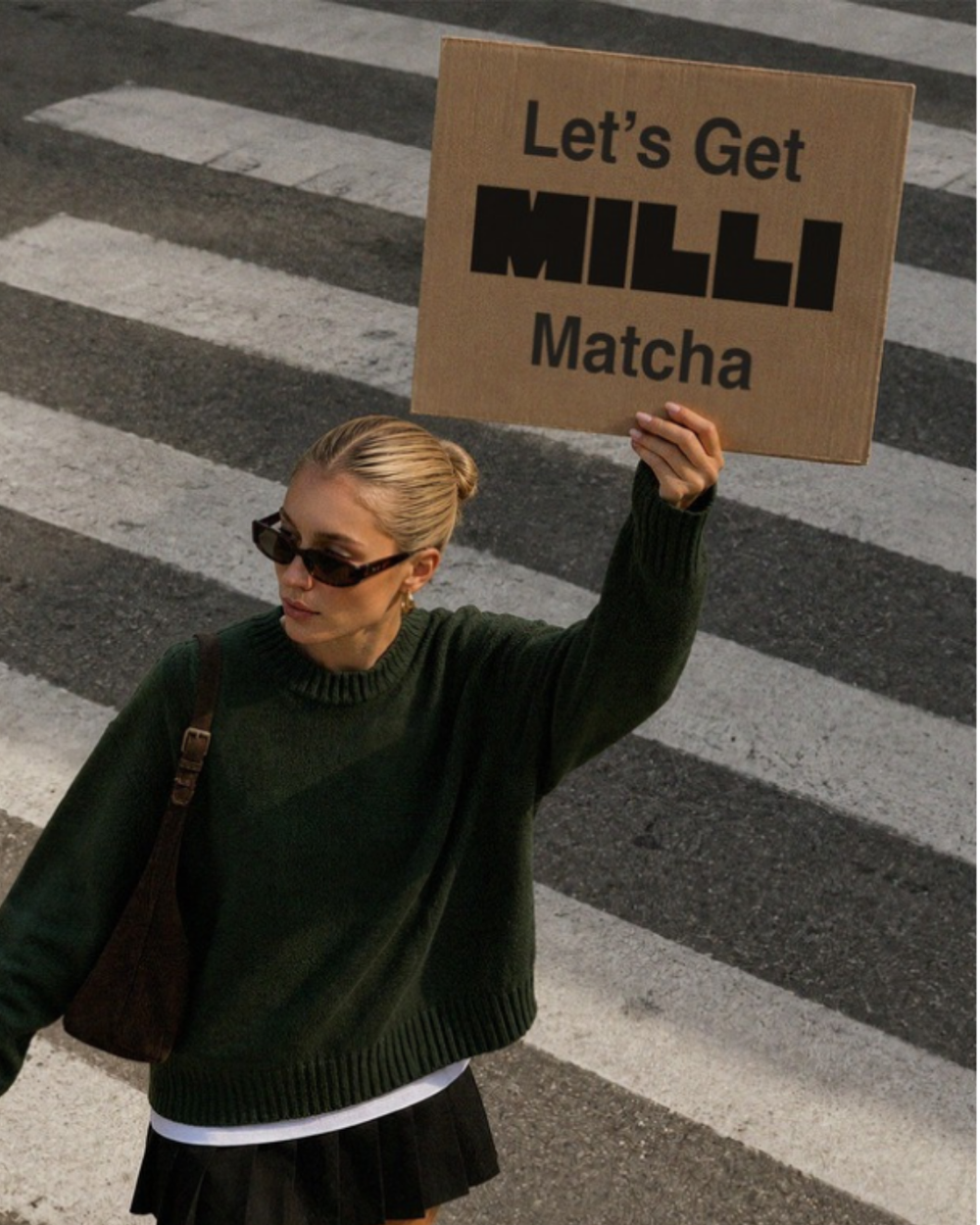 Person holding a sign that reads: Let’s Get MILLI Matcha.
