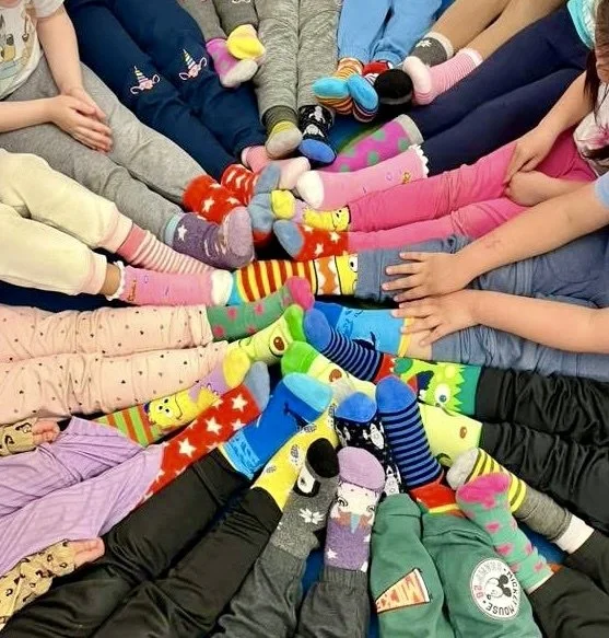 A circle of children's feet in colorful, mismatched socks