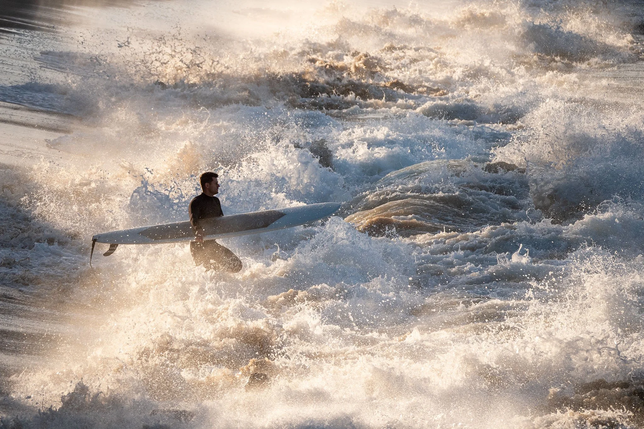 A man surfing on a wave in the ocean at sunset.