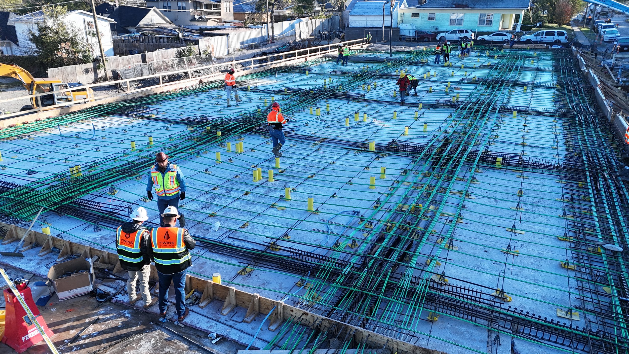 Workers standing beside steel reinforcement and formwork on a construction deck.
