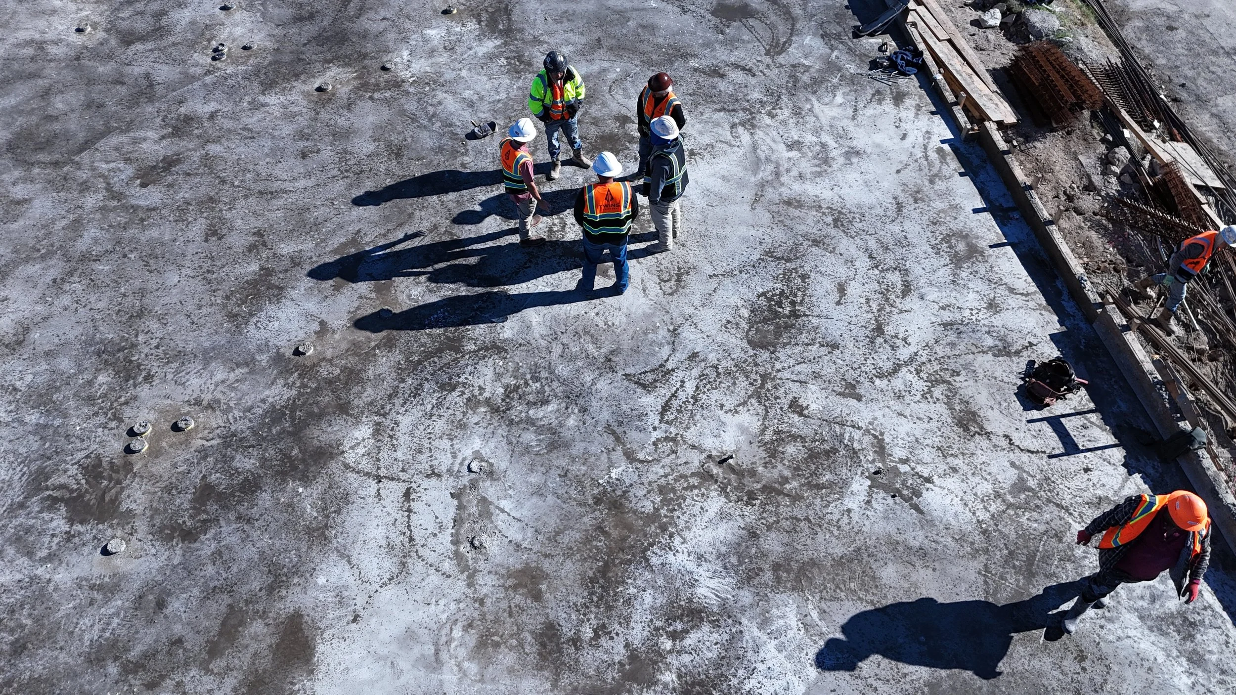 Crew members wearing safety vests on a concrete construction deck.