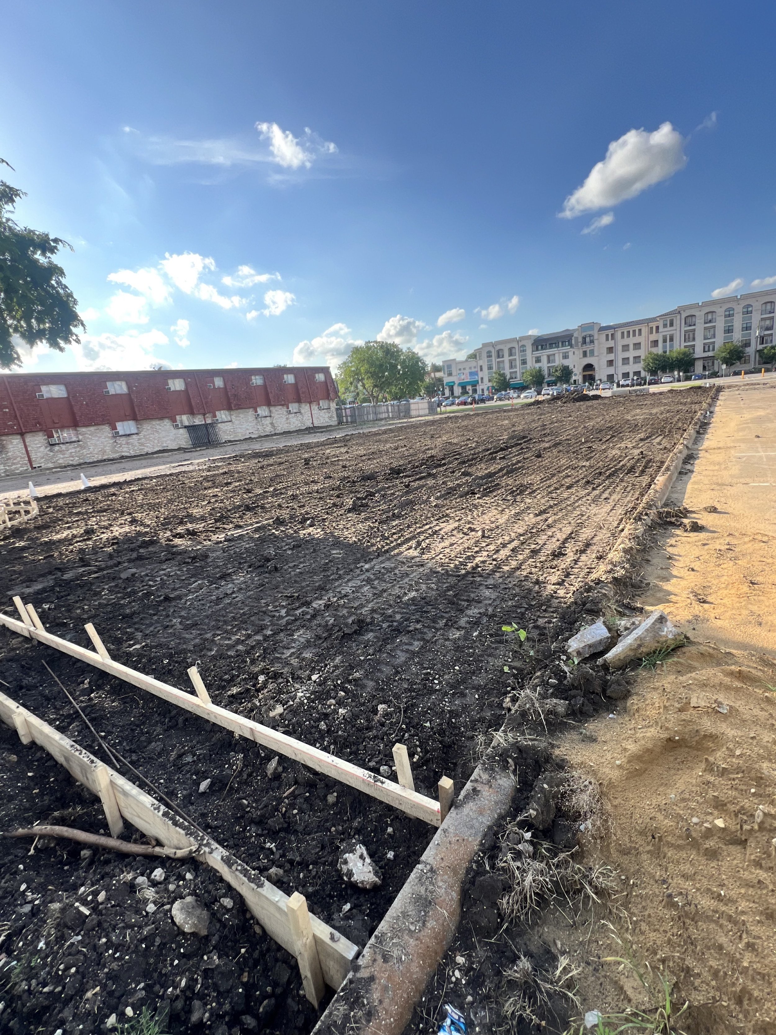 Prepared ground and timber forms along a parking-lot work area.
