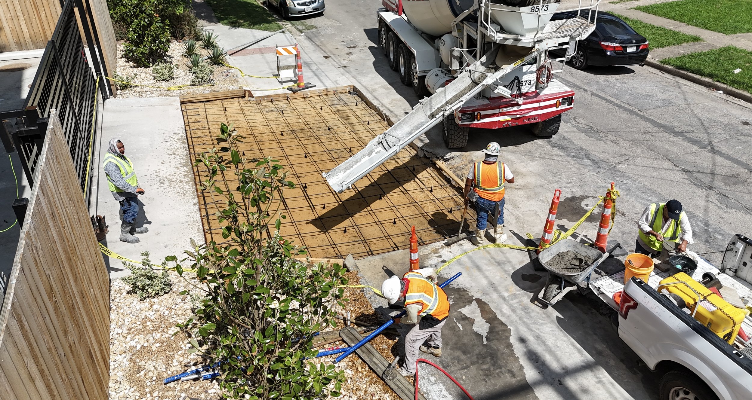 Overhead view of workers and concrete delivery equipment at a reinforced sidewalk work area.