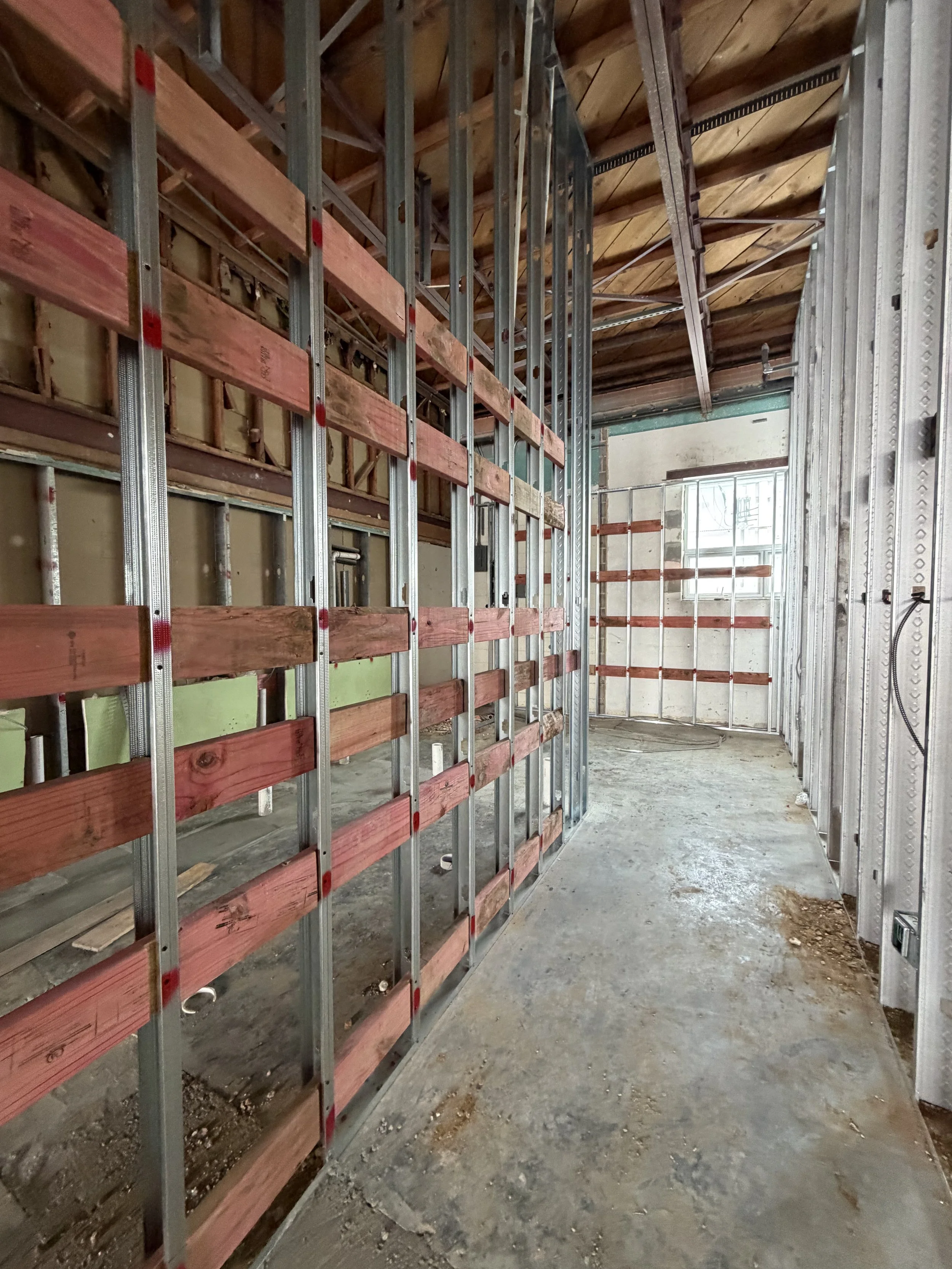 Corridor framed with metal studs and horizontal wood backing on the walls.