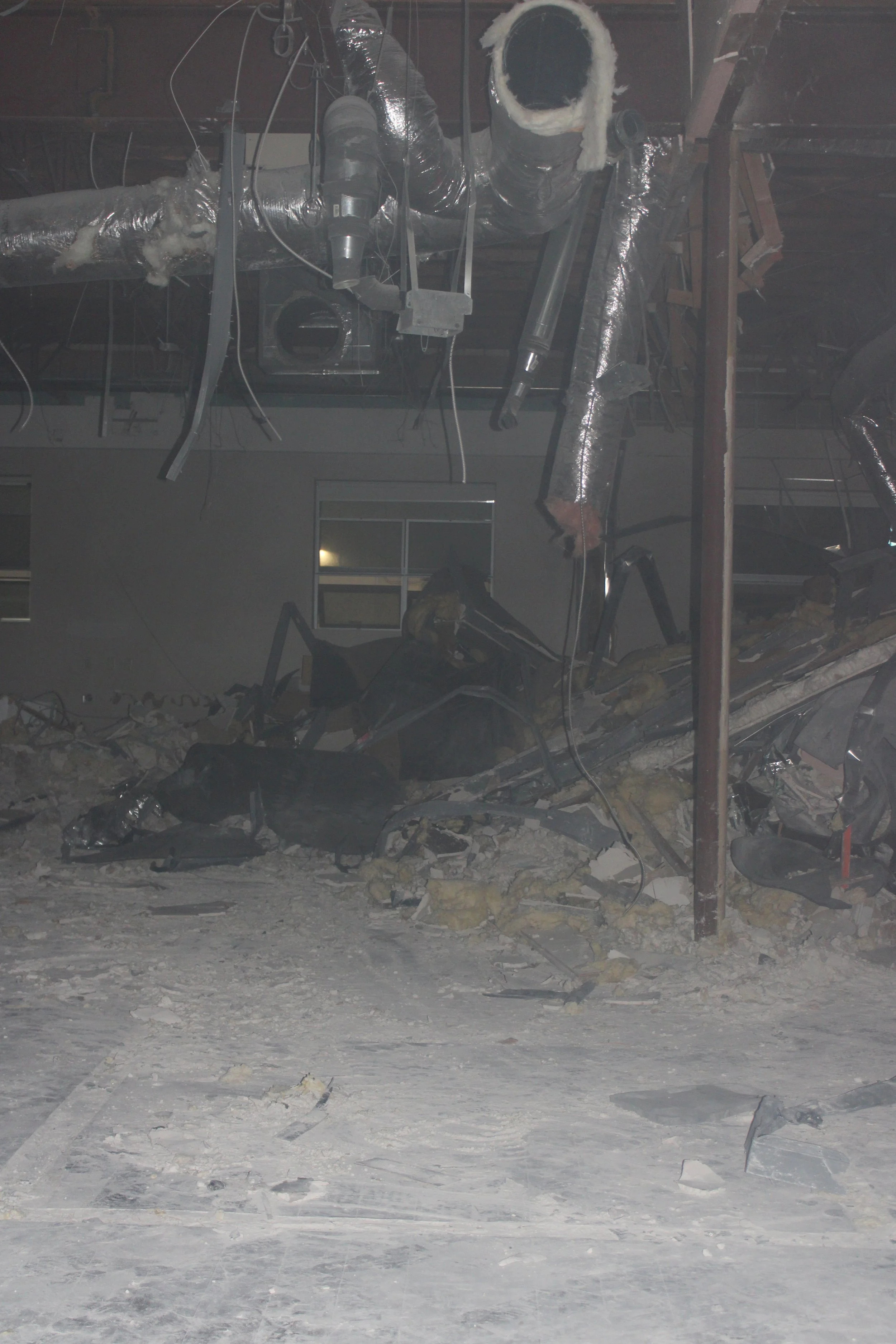 Exposed overhead ducts and pipes above an interior demolition area.