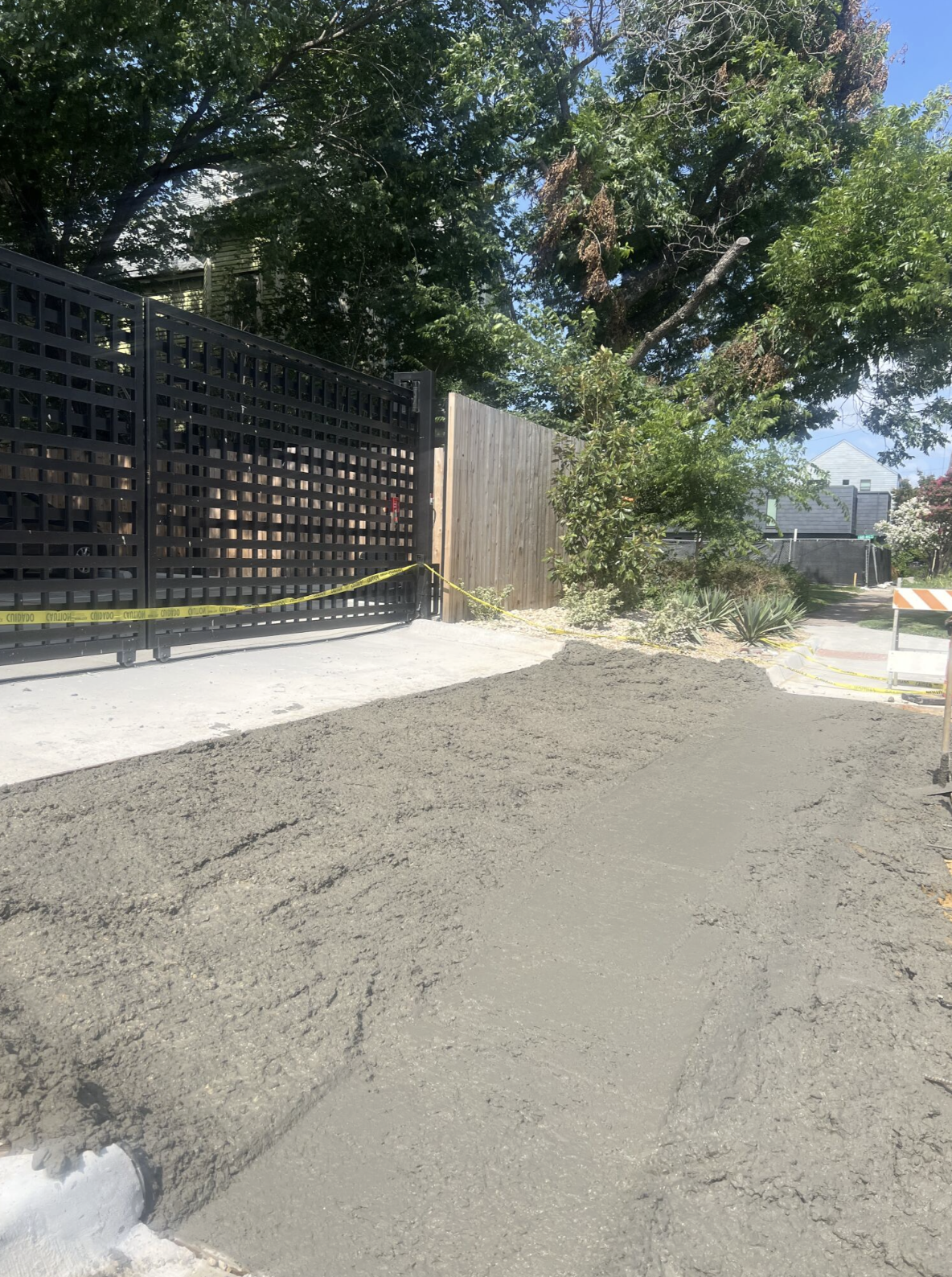 Textured concrete surface on a sidewalk repair beside a black metal gate.