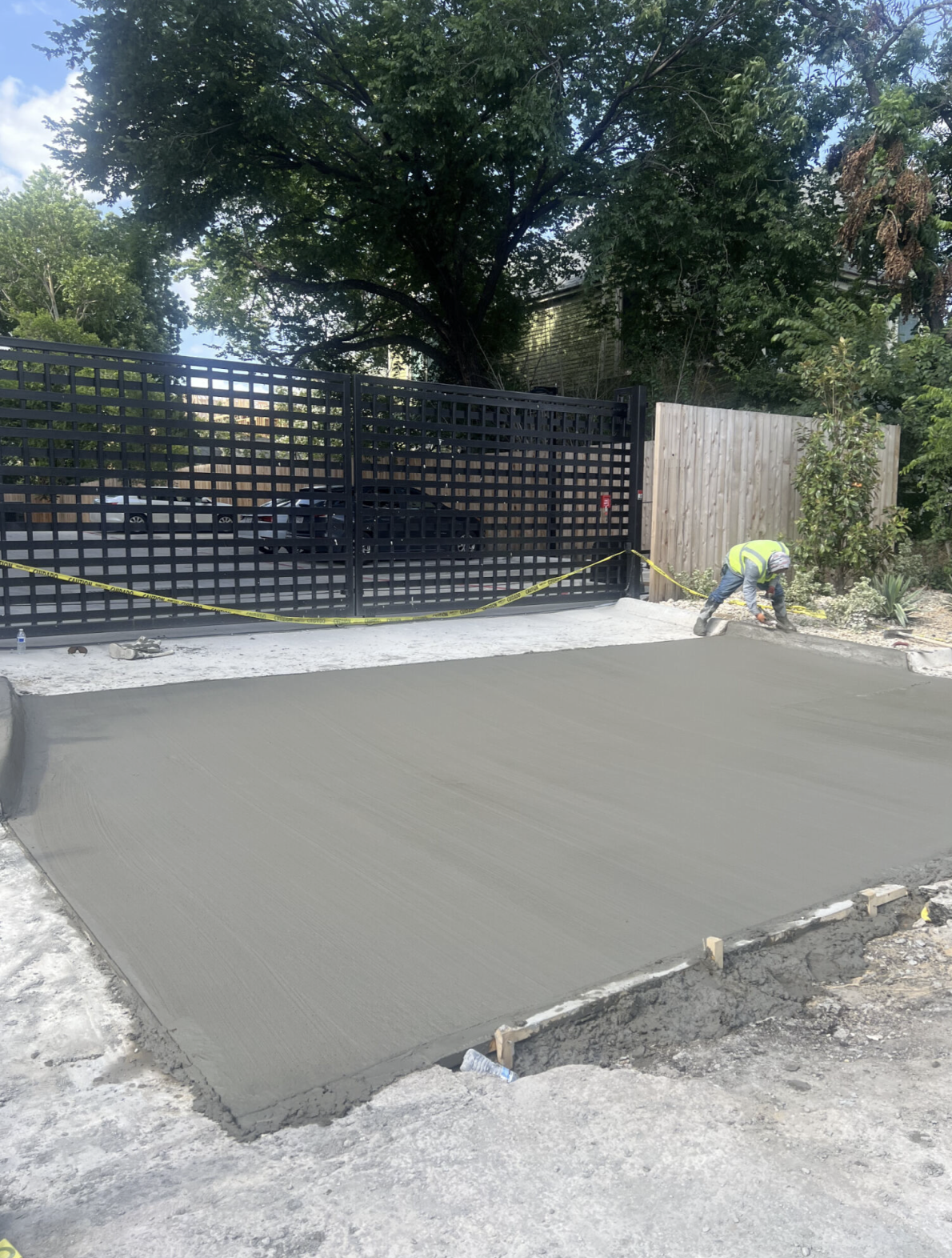Freshly placed concrete sidewalk beside a black metal gate.