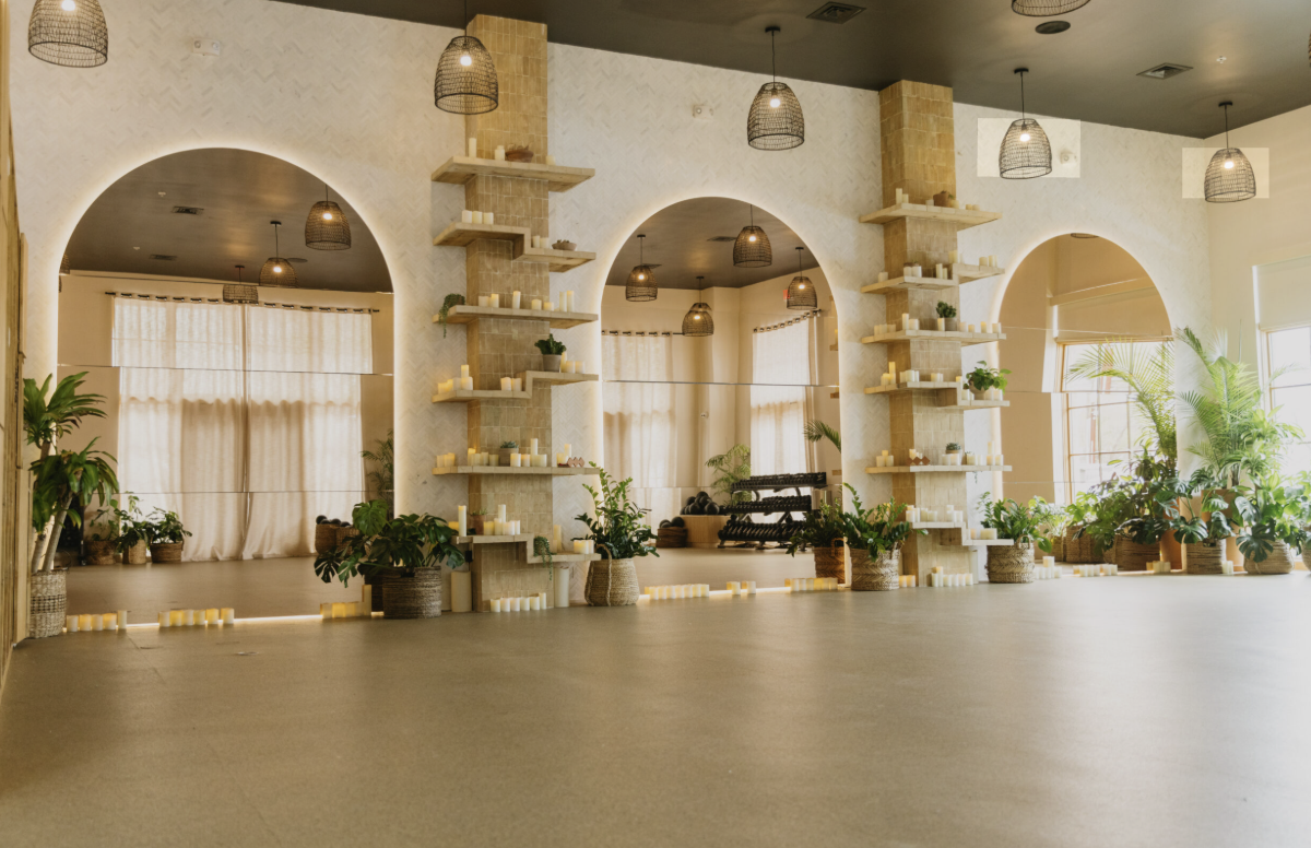 Studio interior with arched mirrors, wooden display shelves, pendant lights, and potted plants.