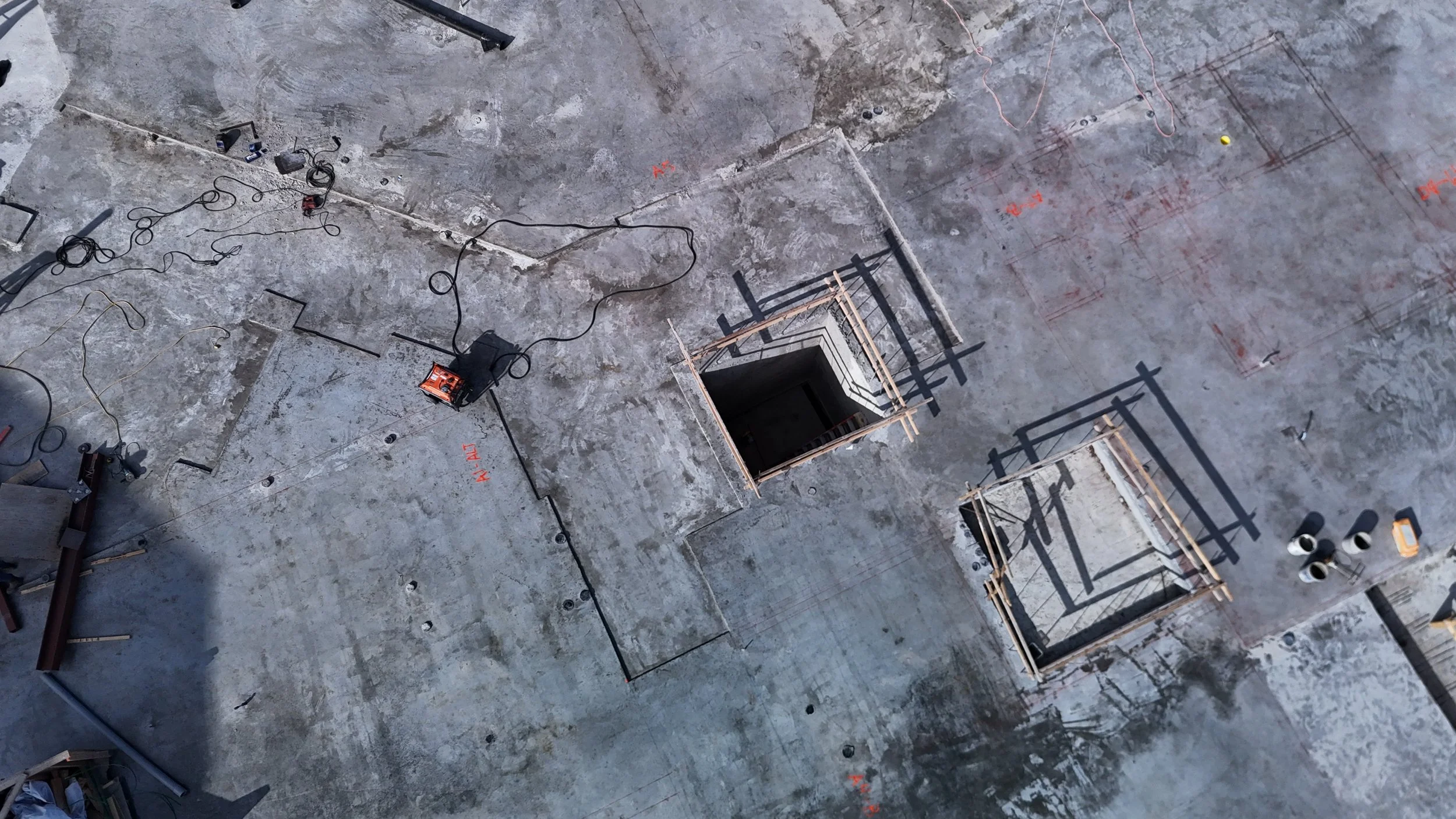 Overhead view of a concrete deck with an opening and projecting steel reinforcement.