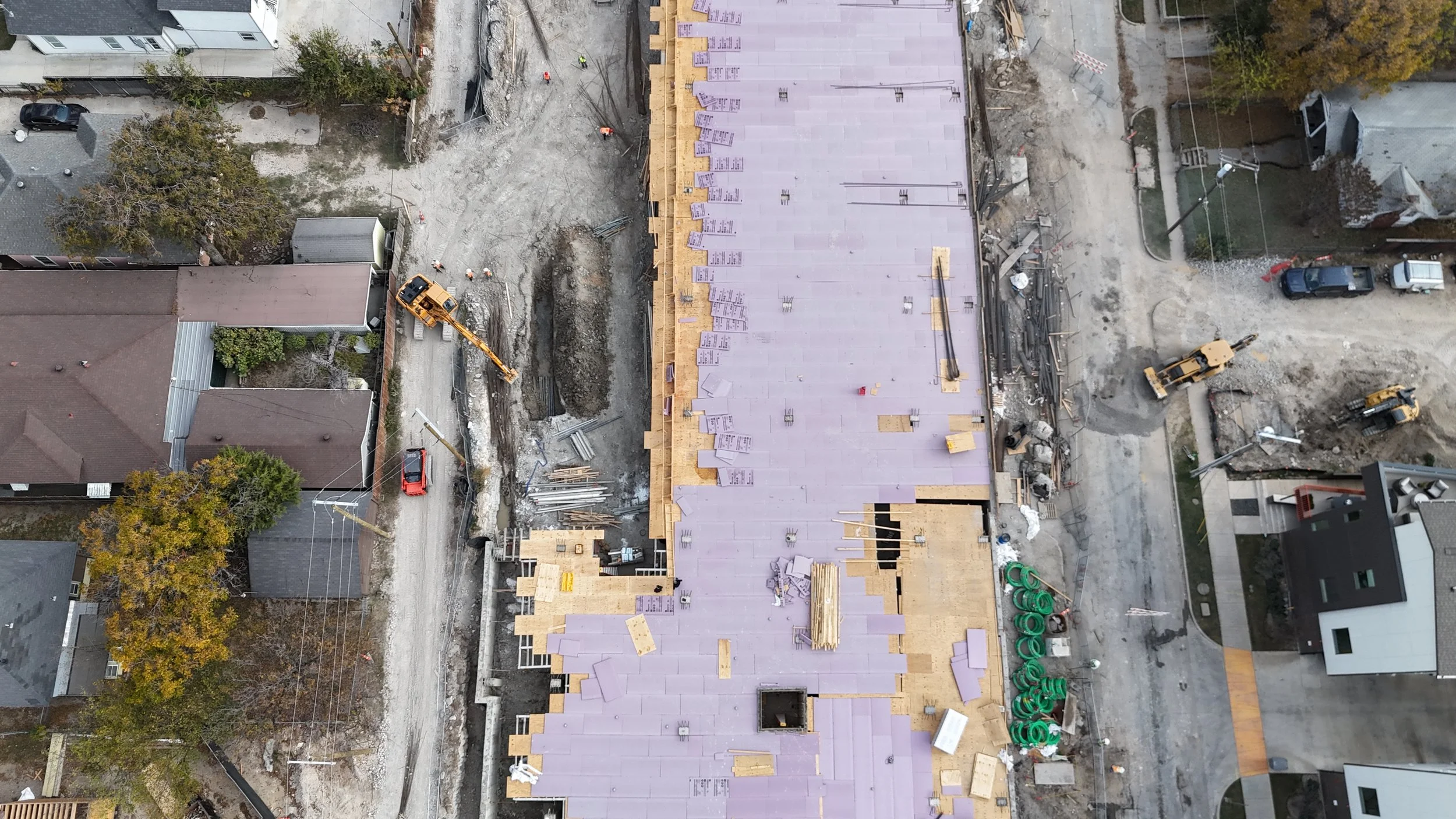 Overhead view of a rectangular construction deck with temporary surface panels, perimeter forms, and openings.