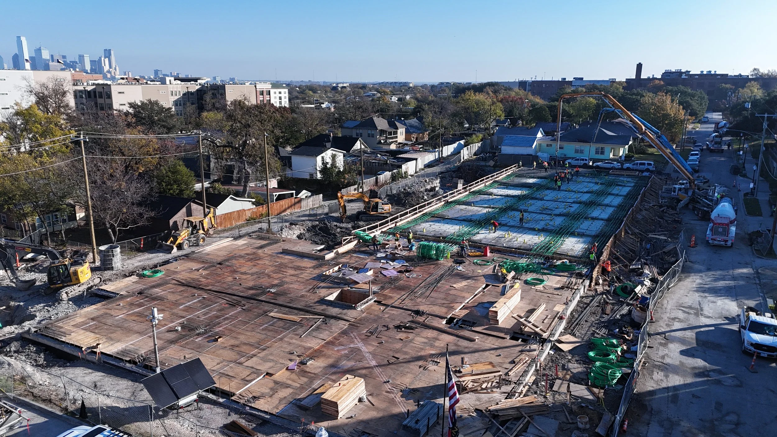 Wide aerial view of an active building site with formwork, materials, and surrounding properties.