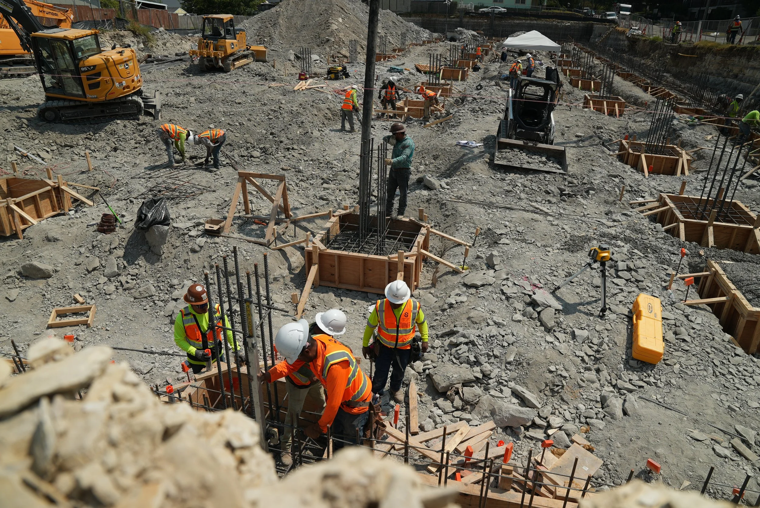 Concrete crew members in high-visibility safety gear preparing a job site.