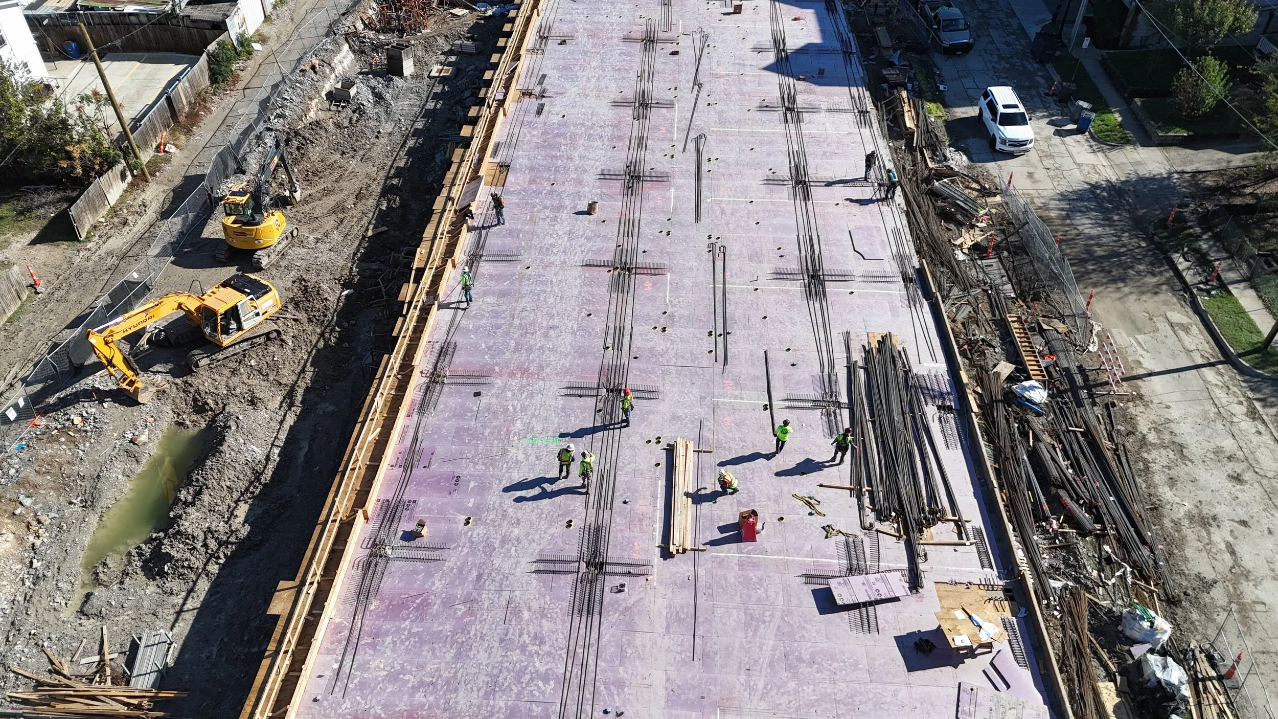 Oblique aerial view of deck preparation with vertical reinforcing bars and temporary perimeter forms.