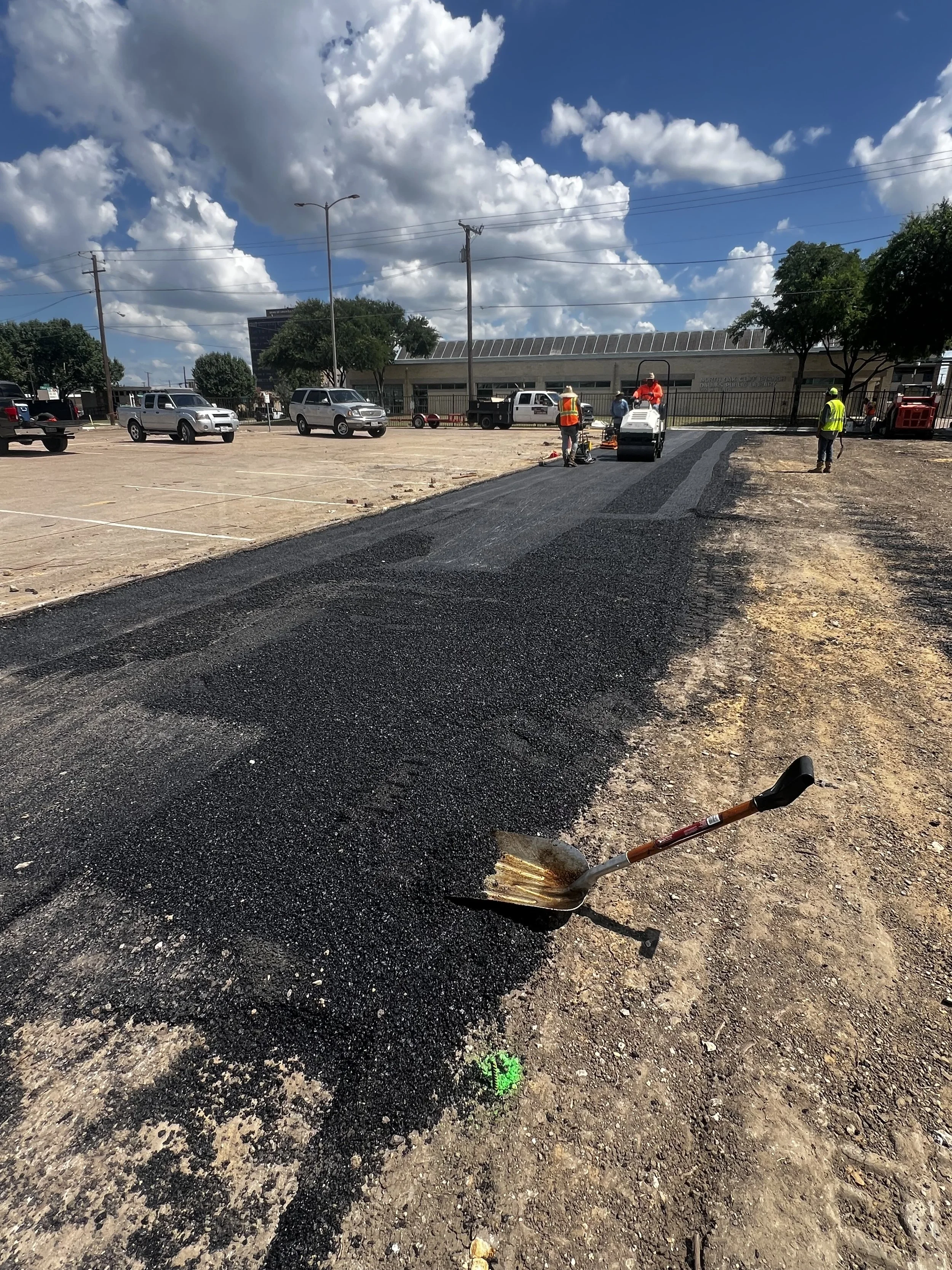 Dark asphalt strip beside a prepared gravel area at a parking lot work site.