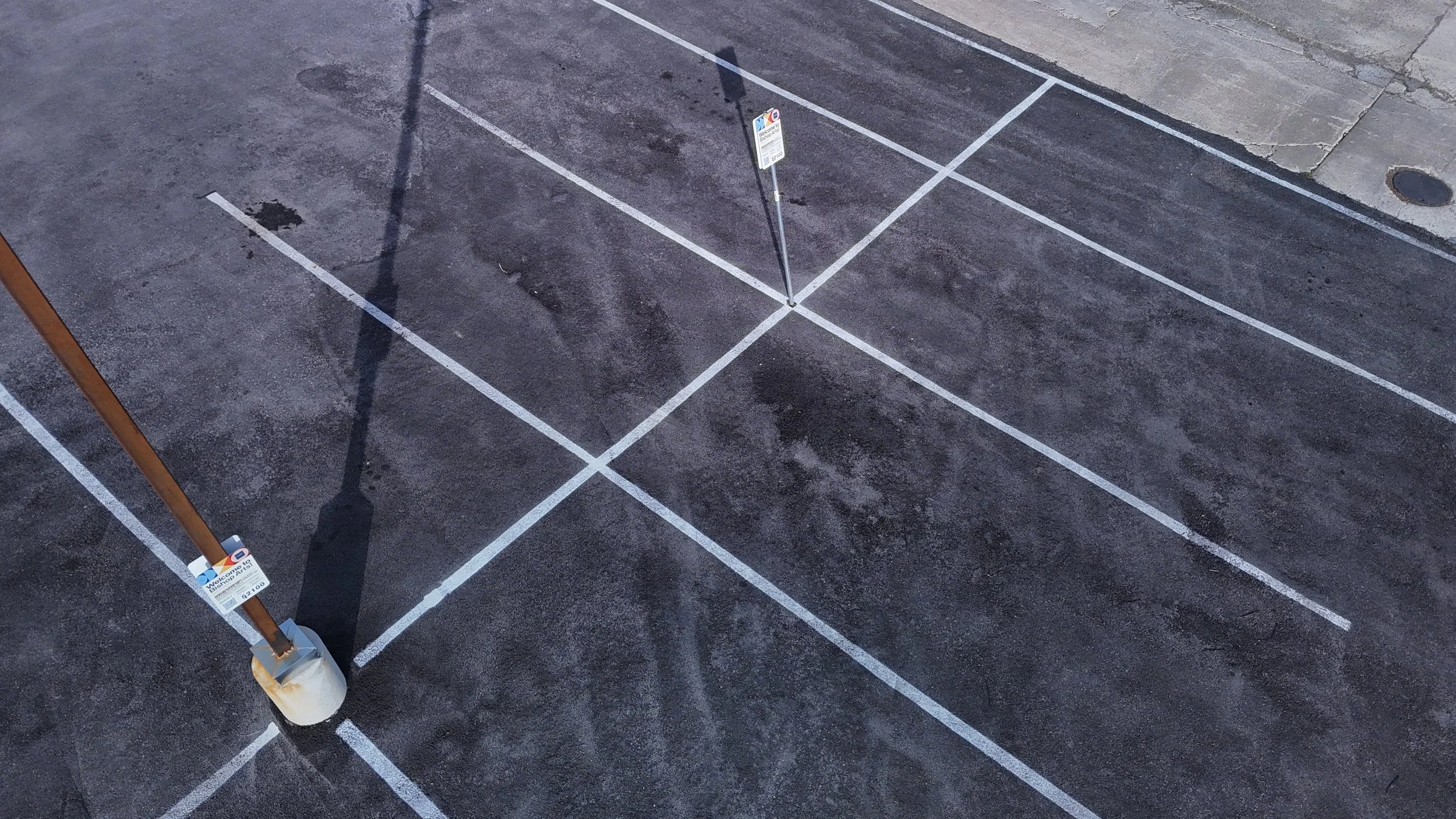Overhead view of white diagonal access-aisle markings and parking signs.