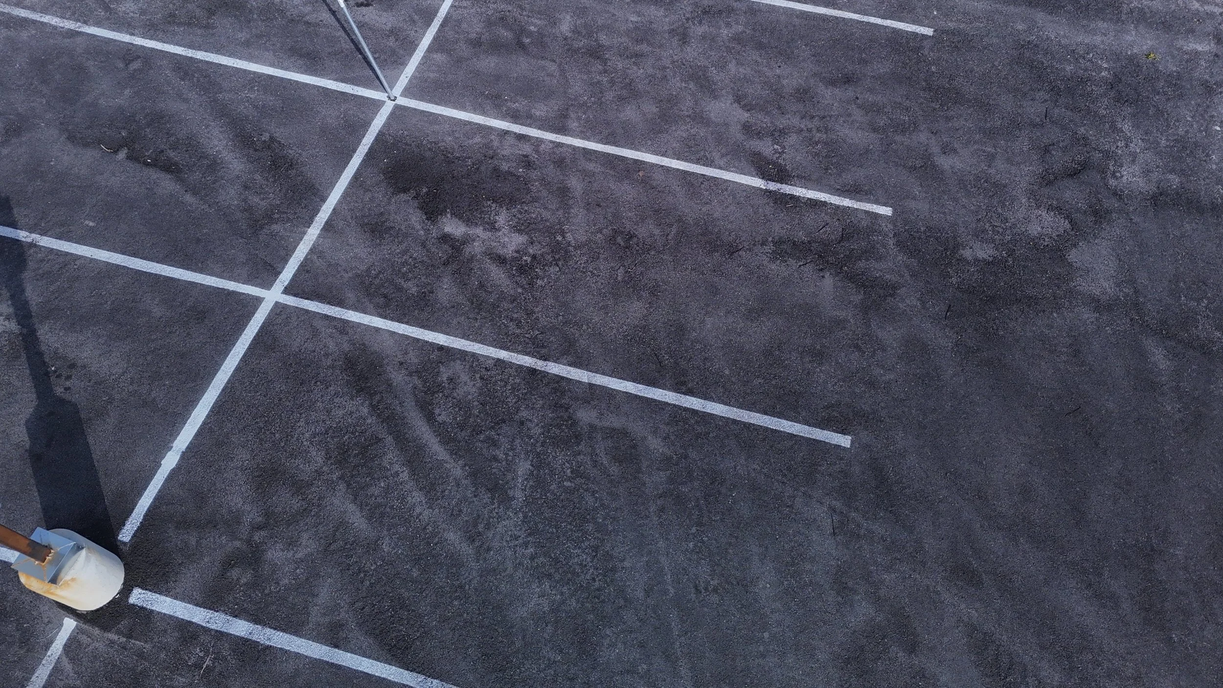 Close overhead view of white parking-space markings on dark asphalt.