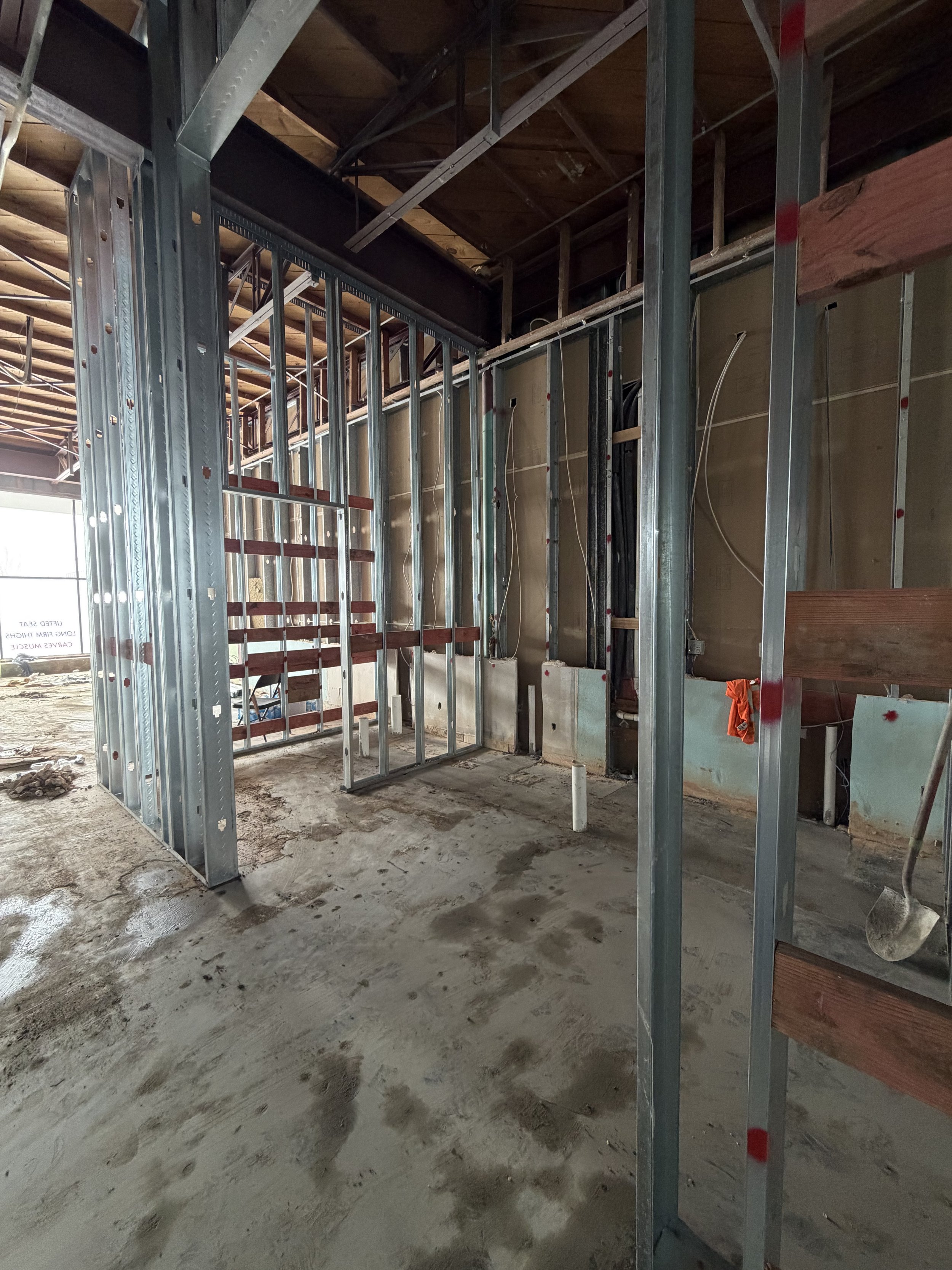 Metal stud partitions with door openings and horizontal wood backing during an interior renovation.
