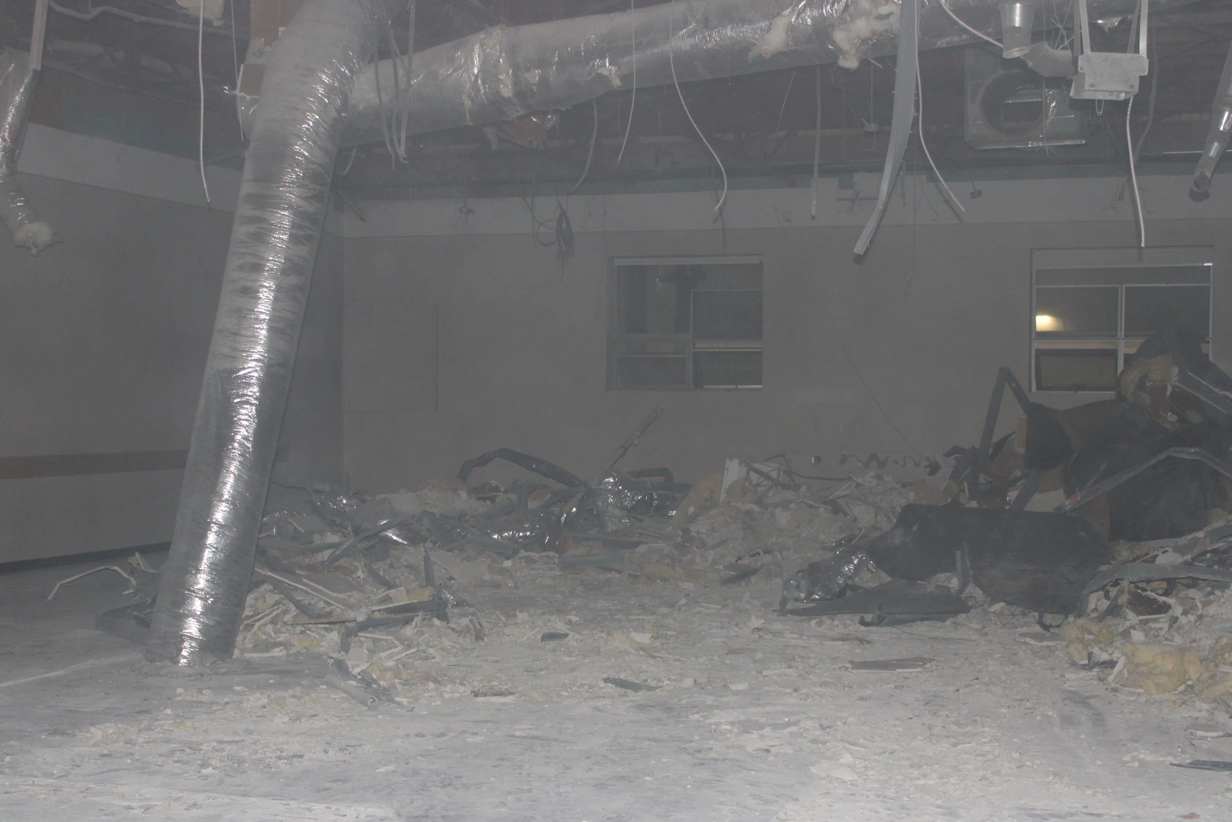 Interior demolition area with rubble across the floor and exposed ceiling ductwork.