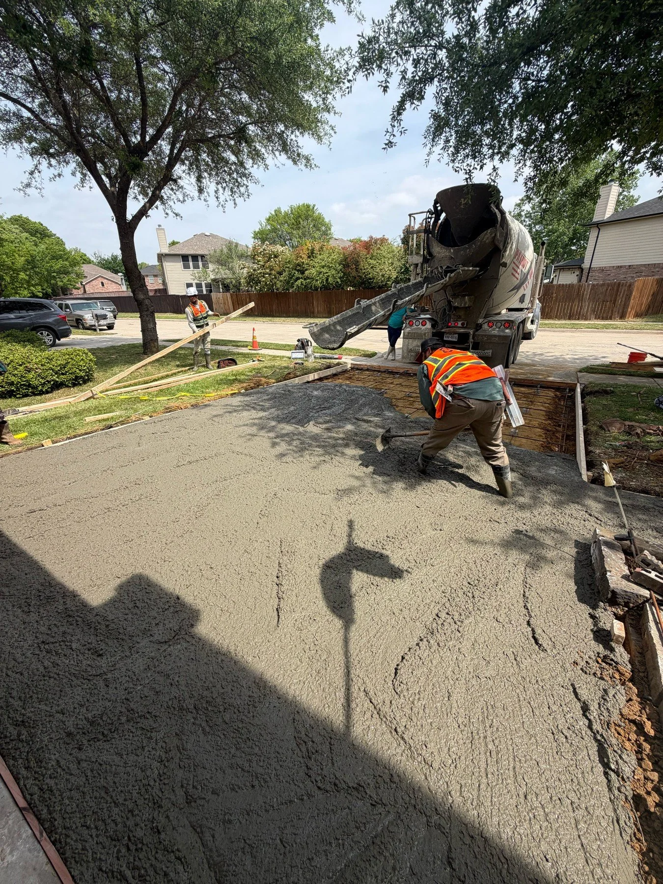 Crew places fresh concrete from a mixer truck into a residential driveway.