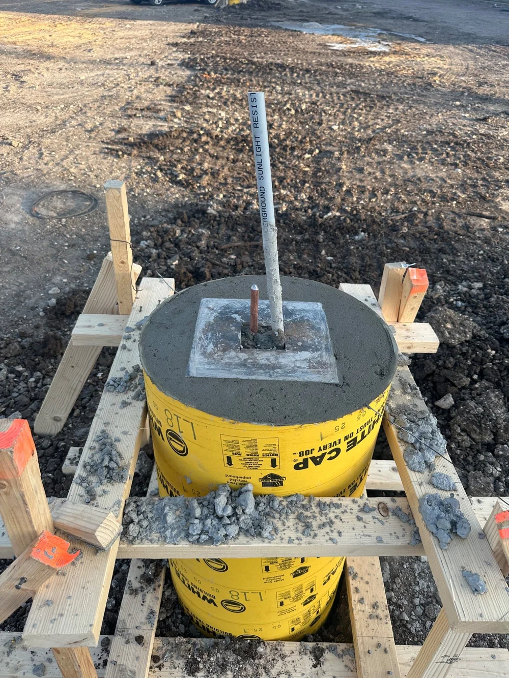 Conduit projecting through a formed concrete base during construction.