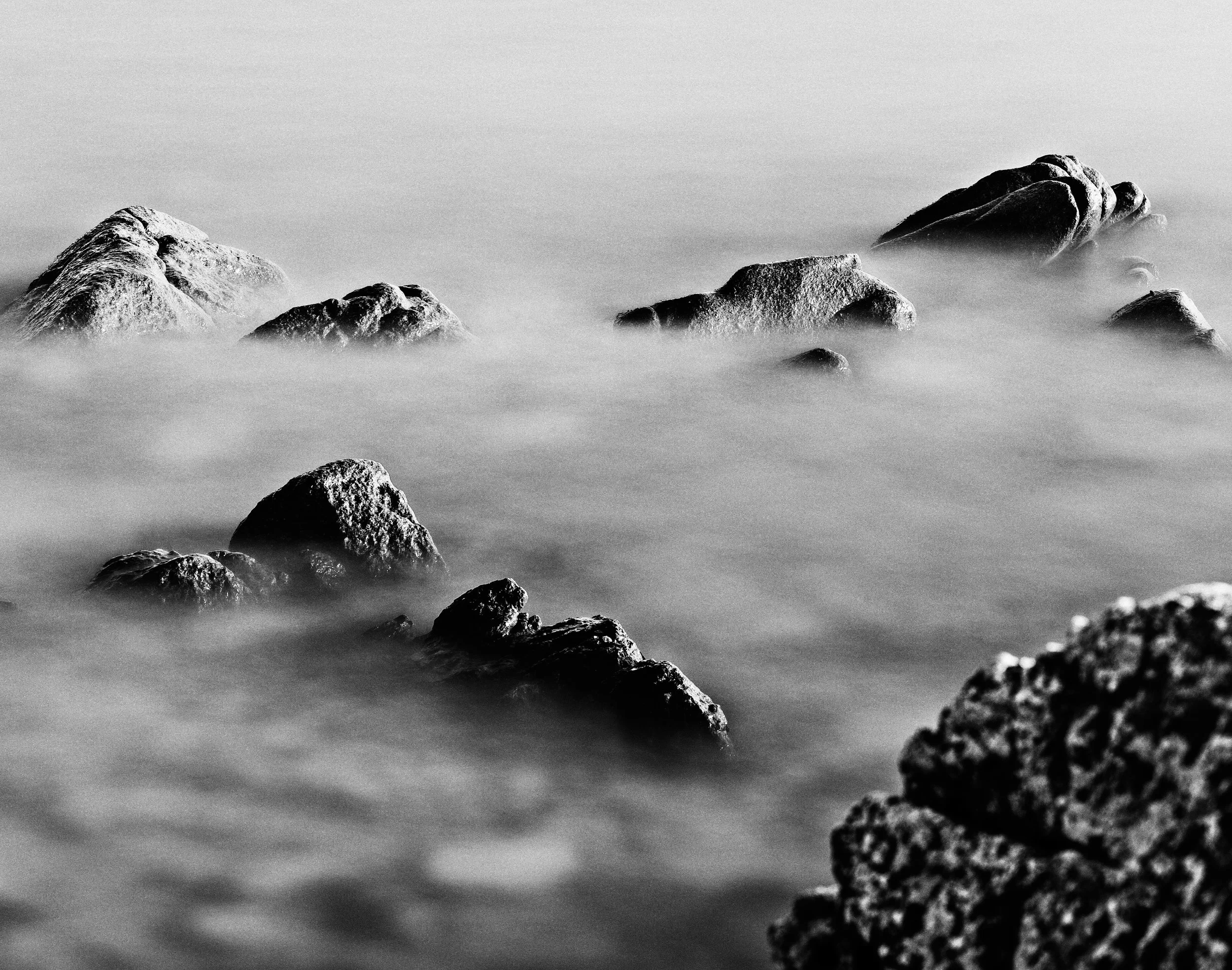Roche en gros plan dans l'eau calme, en noir et blanc.