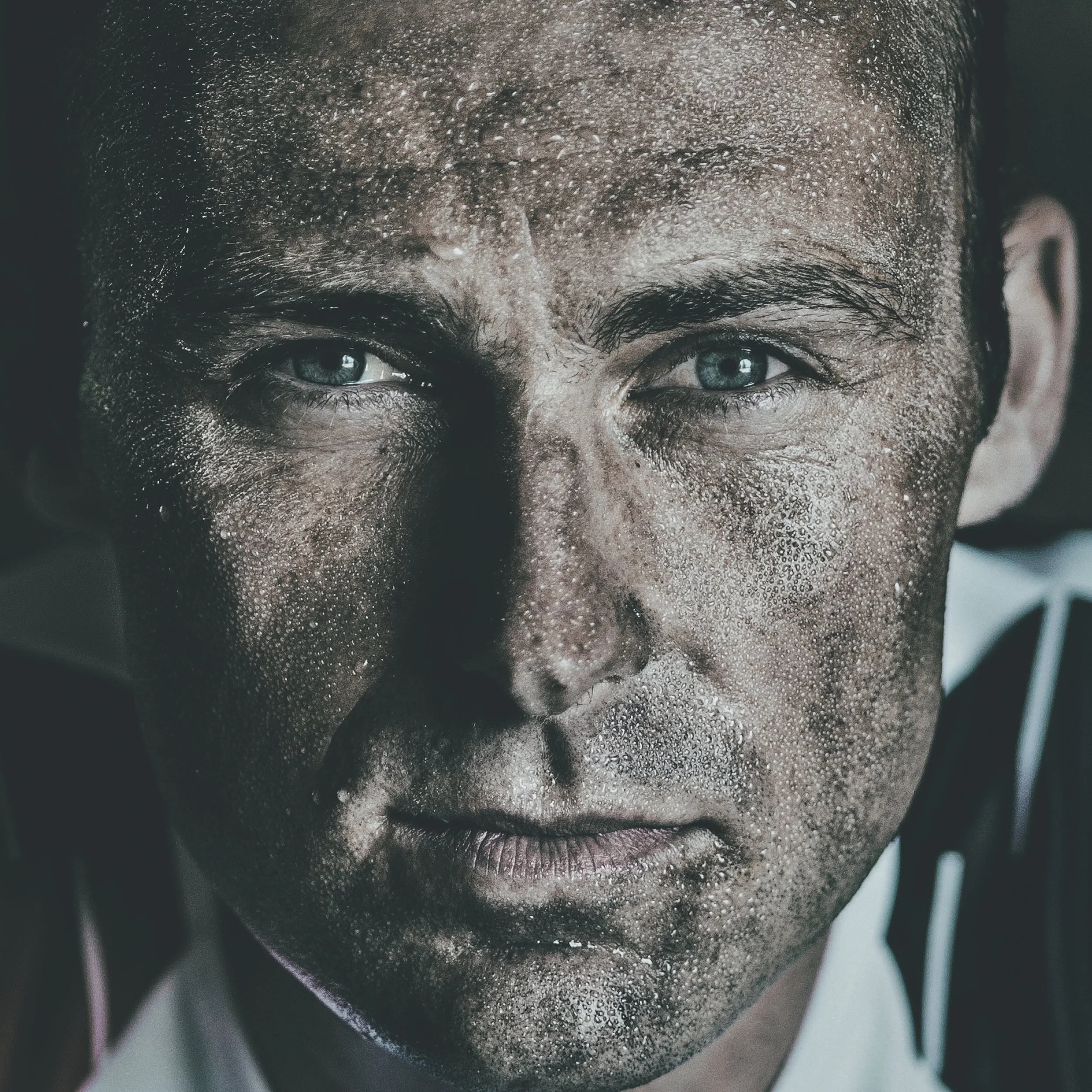 Zoomed-in image of a person's face with visible sweat on forehead, eyes looking forward, partial view of lips, and the corner of a nose, with a blurred background.