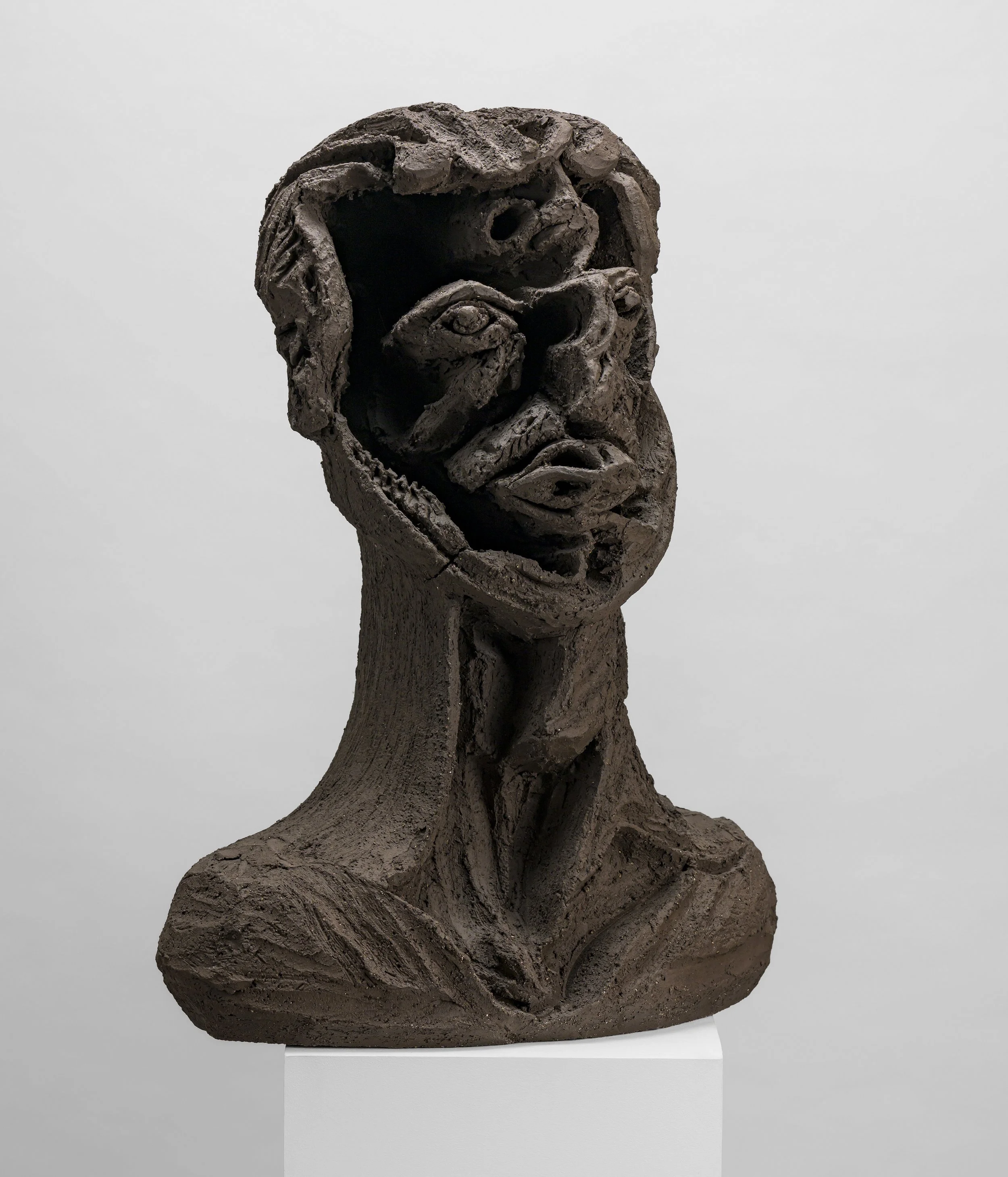 Sculpture en bronze représentant une figure humaine abstraite avec un visage expressif et des détails texturés.