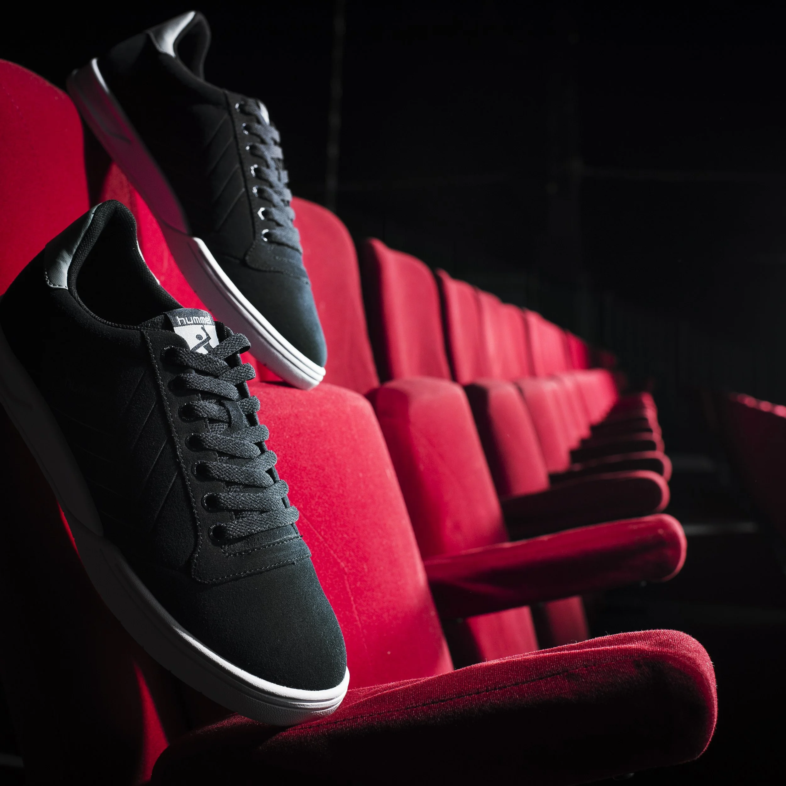 Une chaussure de sport noire posée sur un siège rouge dans un environnement sombre.